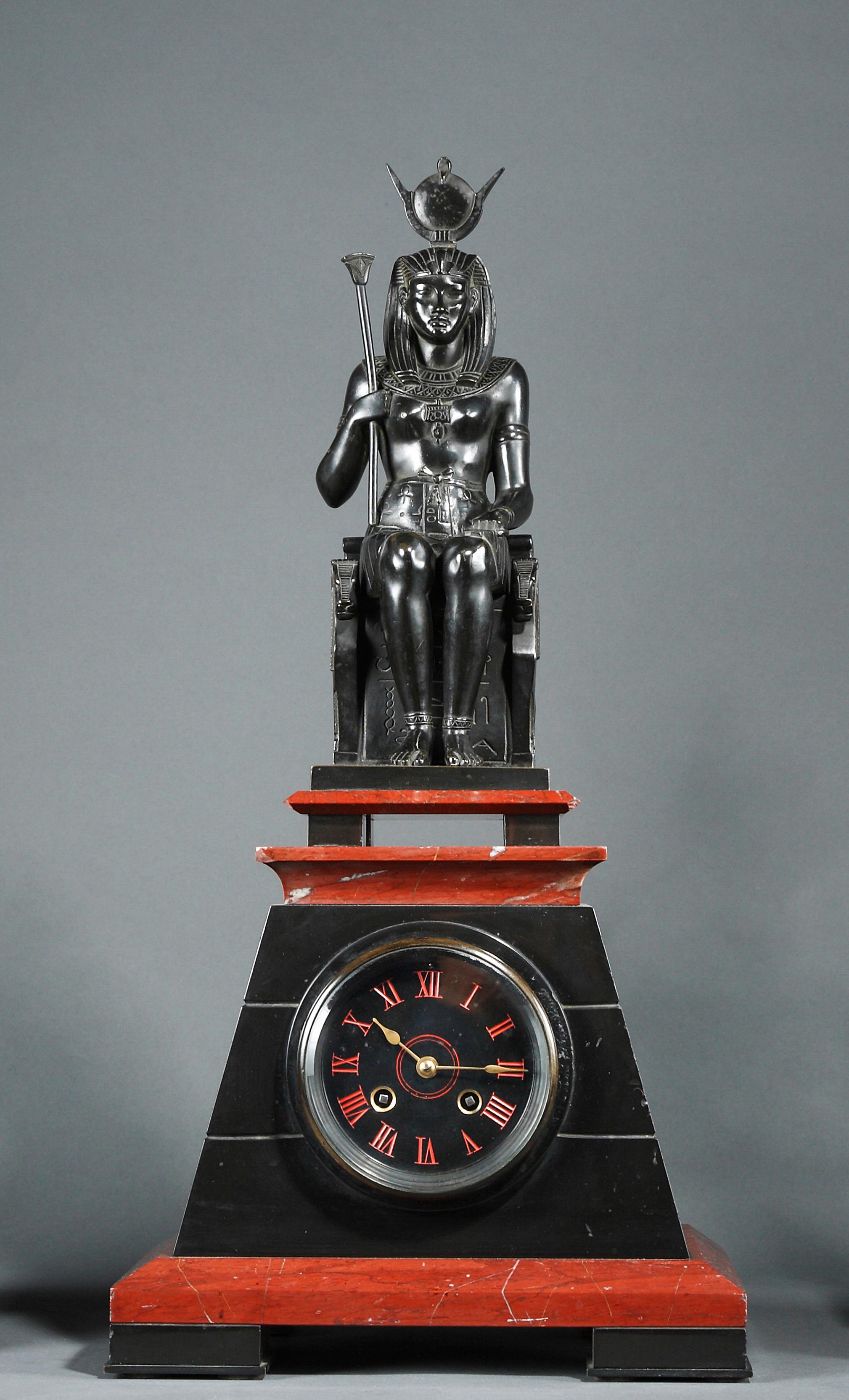 Black and red marble pyramid shaped Egyptian style clock attributed to G. Servant, surmounted by a patinated bronze figure representing the Egyptian goddess Isis sitting on her throne. Wearing the Hathor hairdress (the solar disc surrounded by the