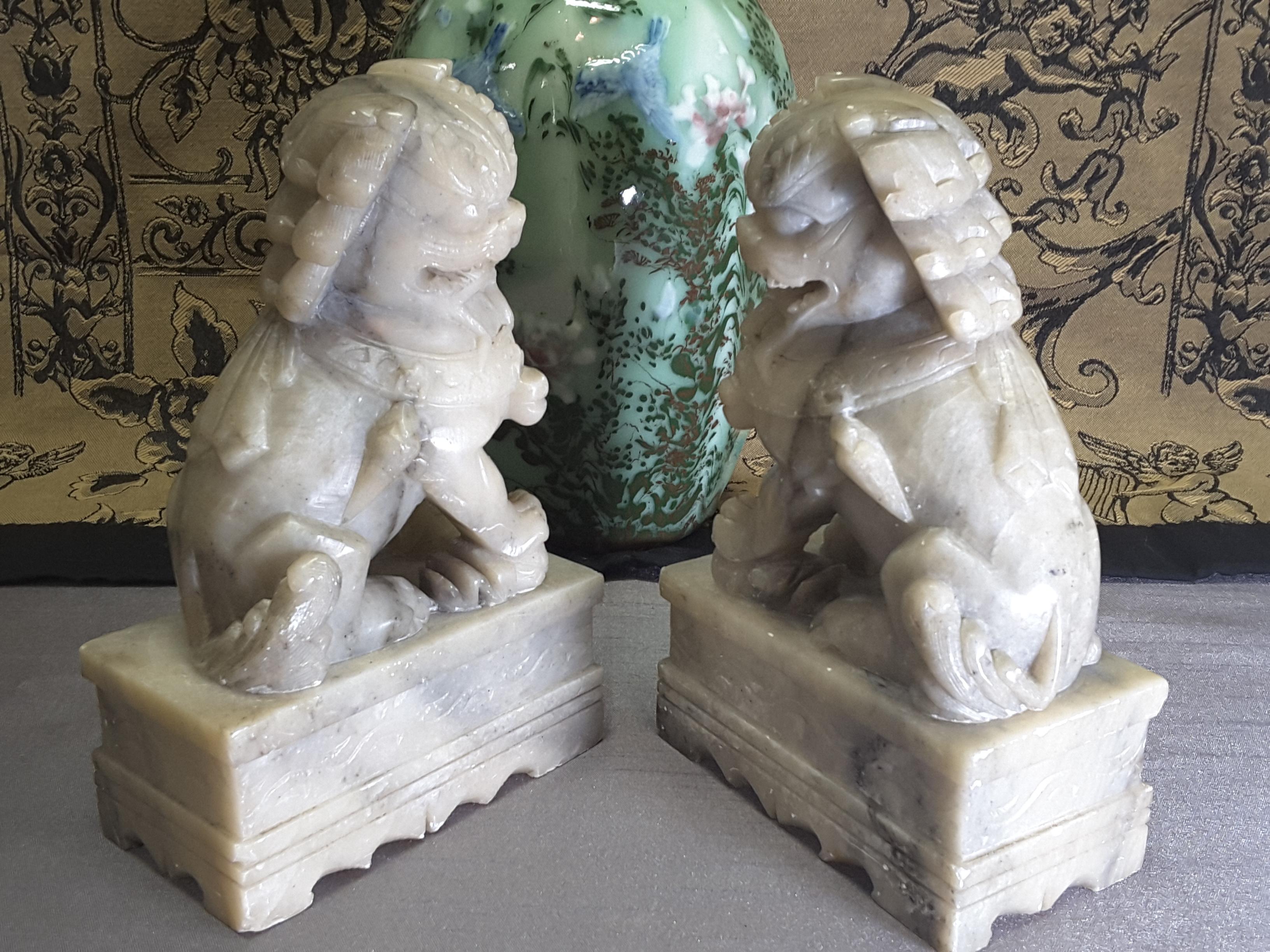 A nice pair of Chinese Foo Dogs/Temple Dogs, carved Soapstone, early 20th century, circa 1920-1930s. The foo dogs are on plinth base with scallop and scroll decoration. The Foo Dogs are opposite facing with one raised paw, minor marks to soapstone