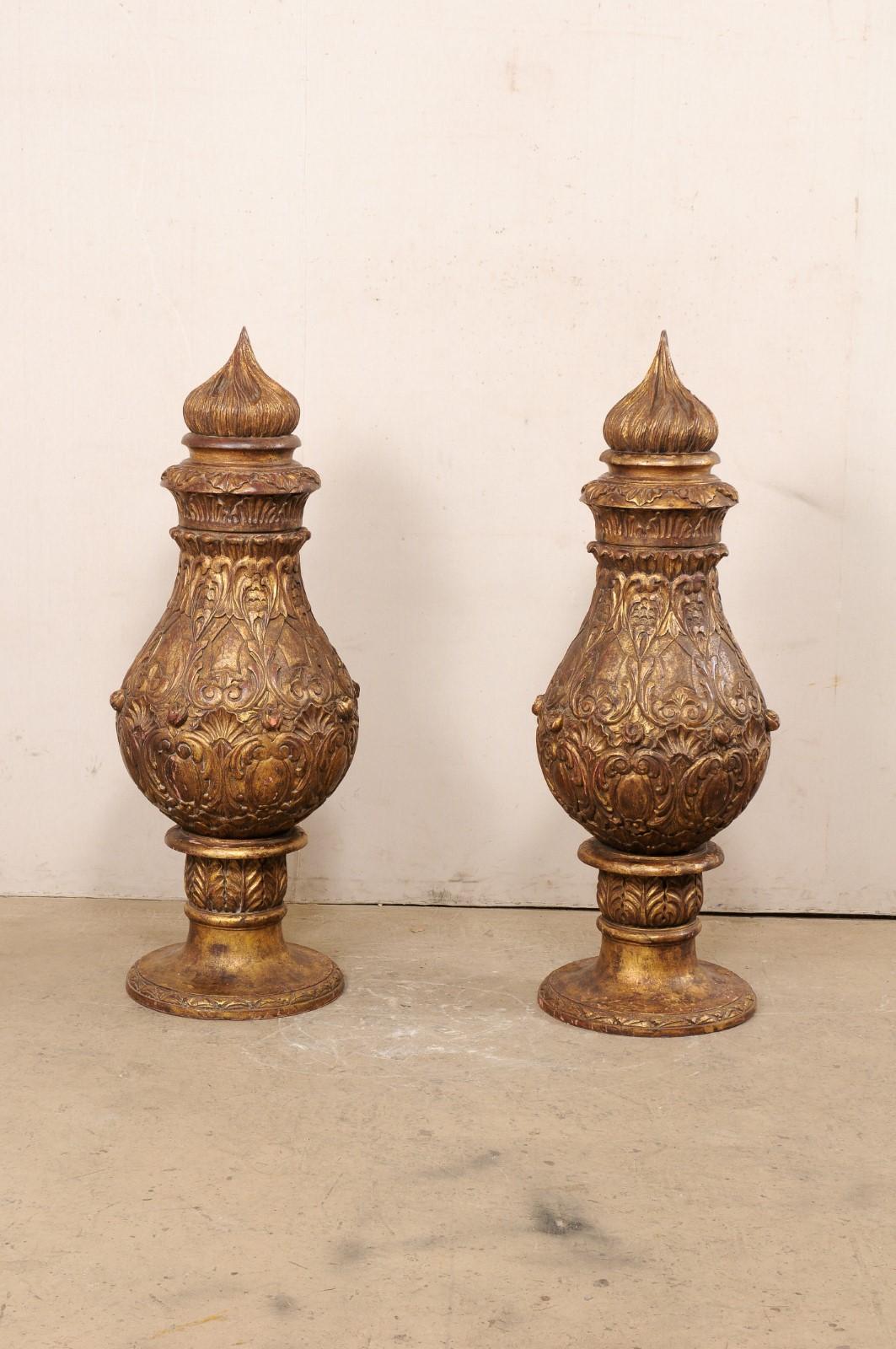 A French pair of large-sized, wood-carved pot à feu (fire urn) finials. This vintage pair of finials from France, each standing just over five feet in height, have teardrop-shaped urn bodies embellished in a shell, scroll, and acanthus leaf motif,