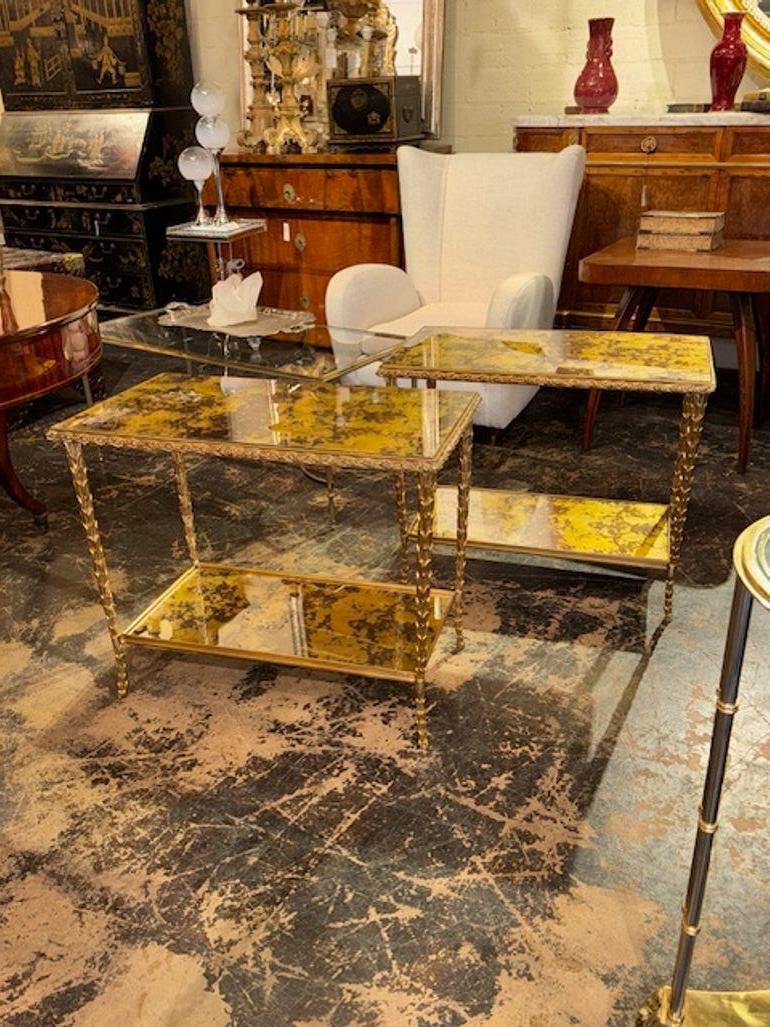 El producto es un par de mesas auxiliares italianas de bronce dorado Maison Bagues Manner. Las mesas están fabricadas con intrincados detalles de bronce dorado y cristal pintado al revés, y presentan elementos de diseño elegantes y lujosos. Estas