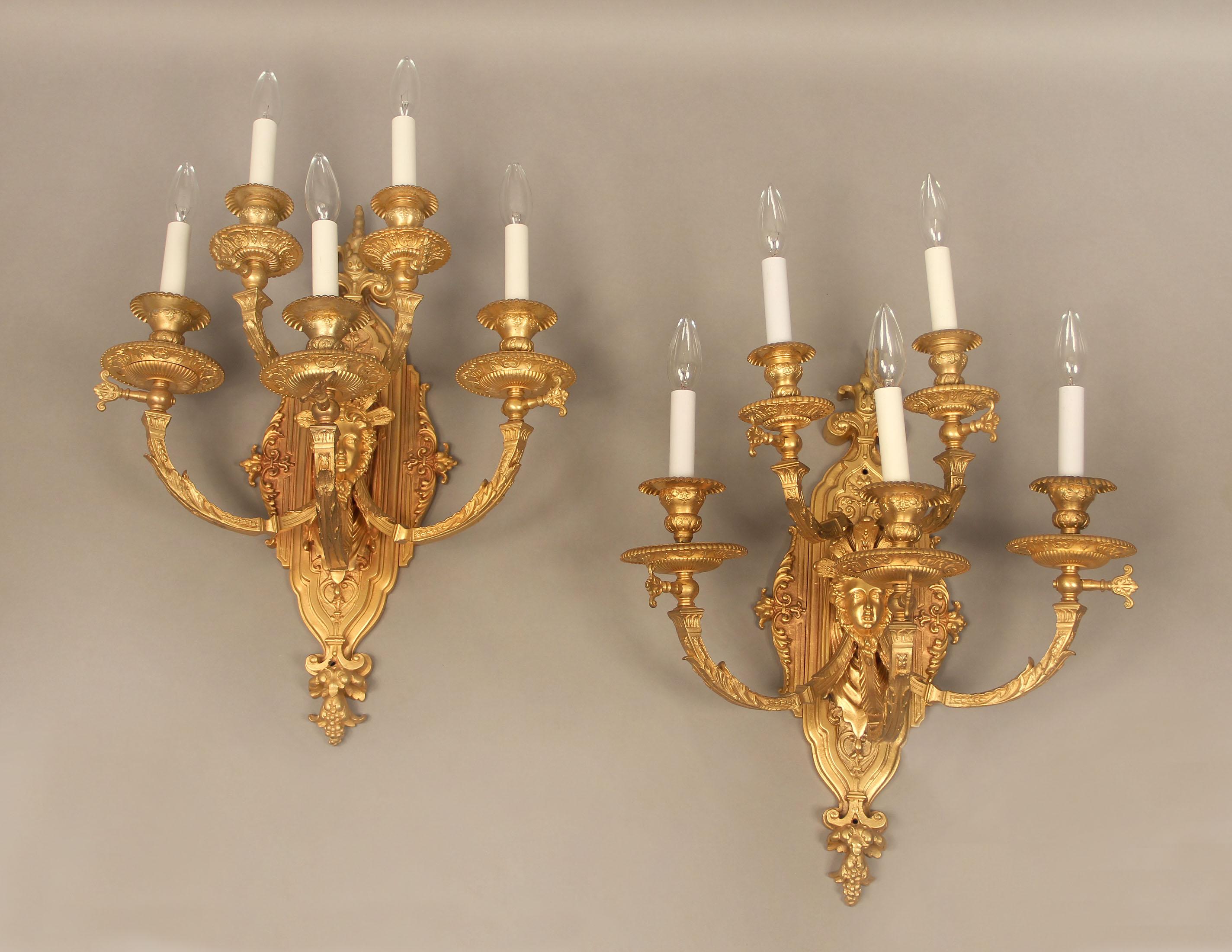 A pair of late 19th century gilt bronze five light sconces

with foliate-scrolled arms and backplate, centered by a female mask and five tiered lights.
