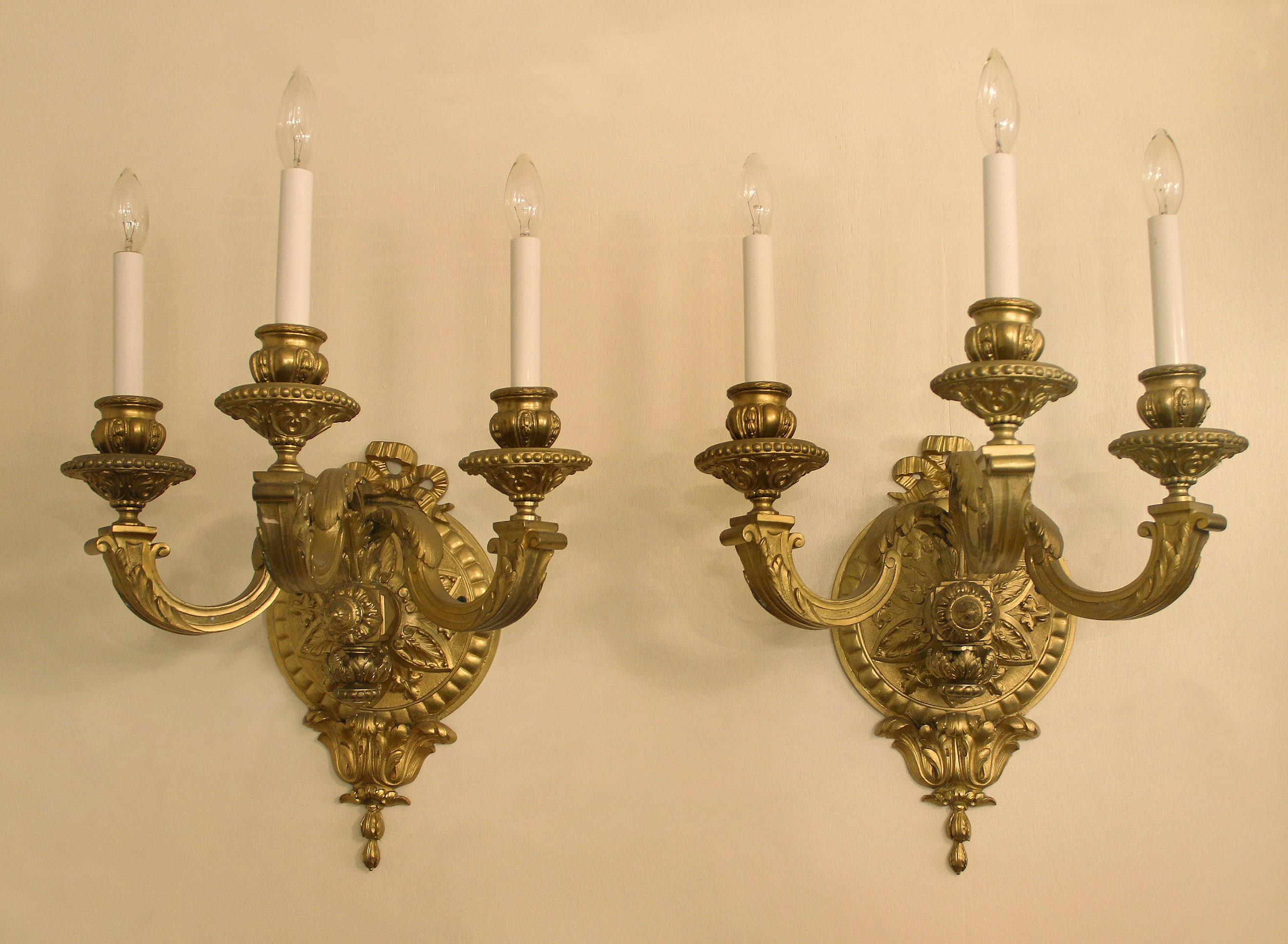 A Nice Pair of late 19th century gilt bronze three light sconces.

Each decorated with a bow above a circular backplate centered with a star and floral design and three “S” shaped arms.
