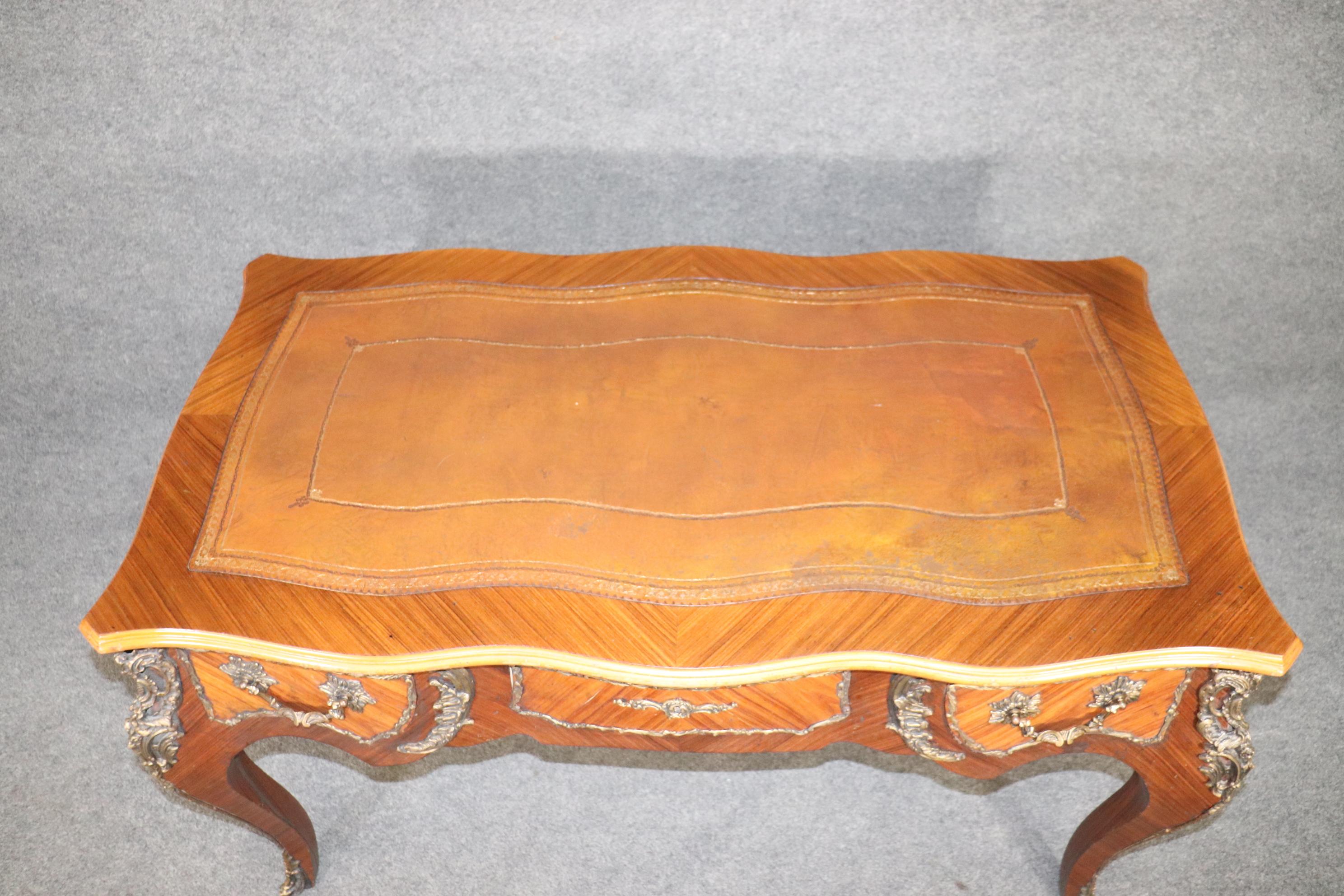 This French Louis XV style leather top desk with brass accents is made of the highest quality and really separates itself from other desks with its attention to detail and elaborate floral decorations on the brass castings. This piece is equipped
