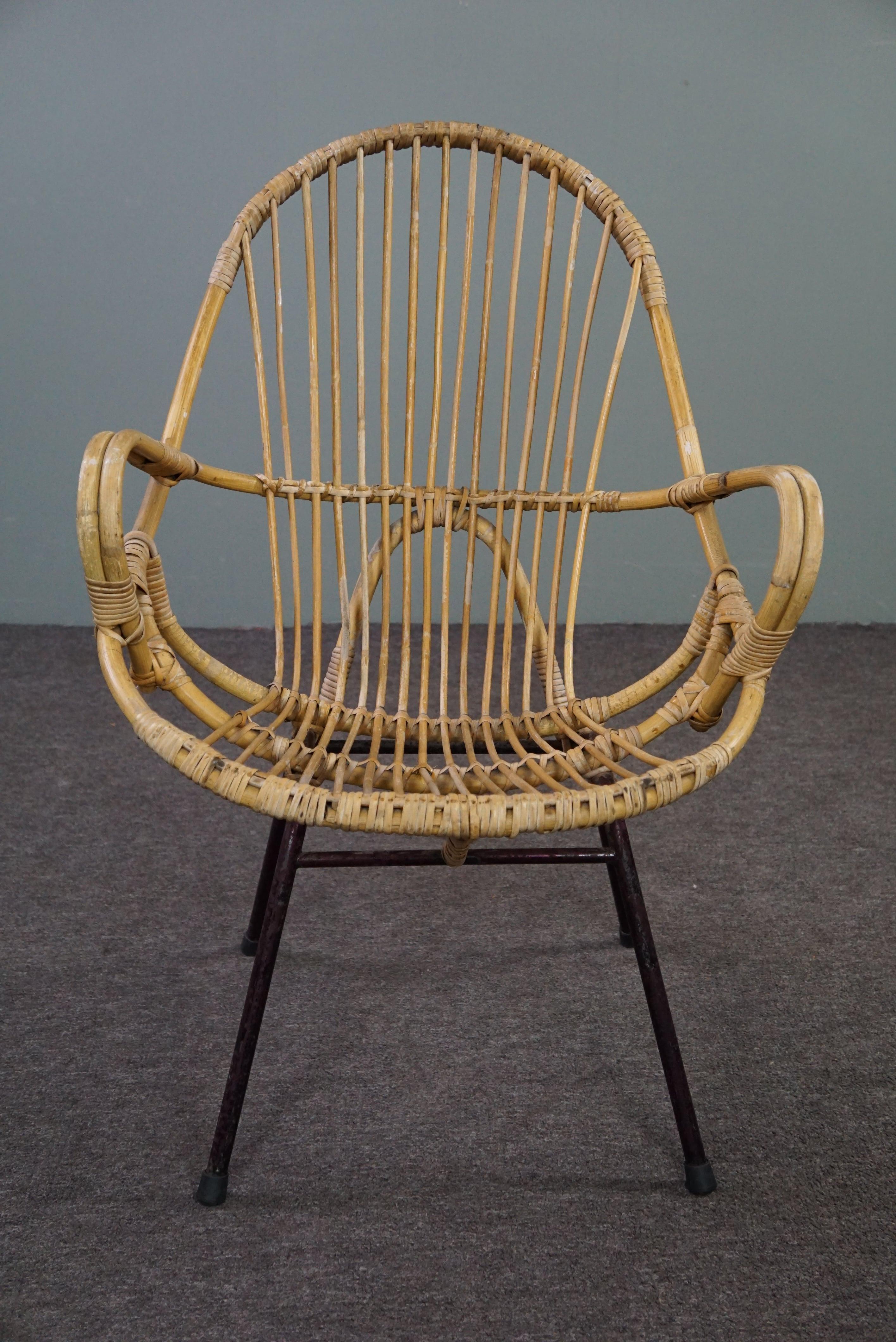 Ce magnifique fauteuil avec accoudoirs a été fabriqué dans les années 1960 aux Pays-Bas.

Ce joli fauteuil en rotin présente un design saisissant. Le fauteuil a un look moderne et les accoudoirs rendent le confort d'assise très agréable. Le