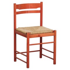 Belle chaise vintage rouge en bois des années 1970 avec une assise en osier tressé.