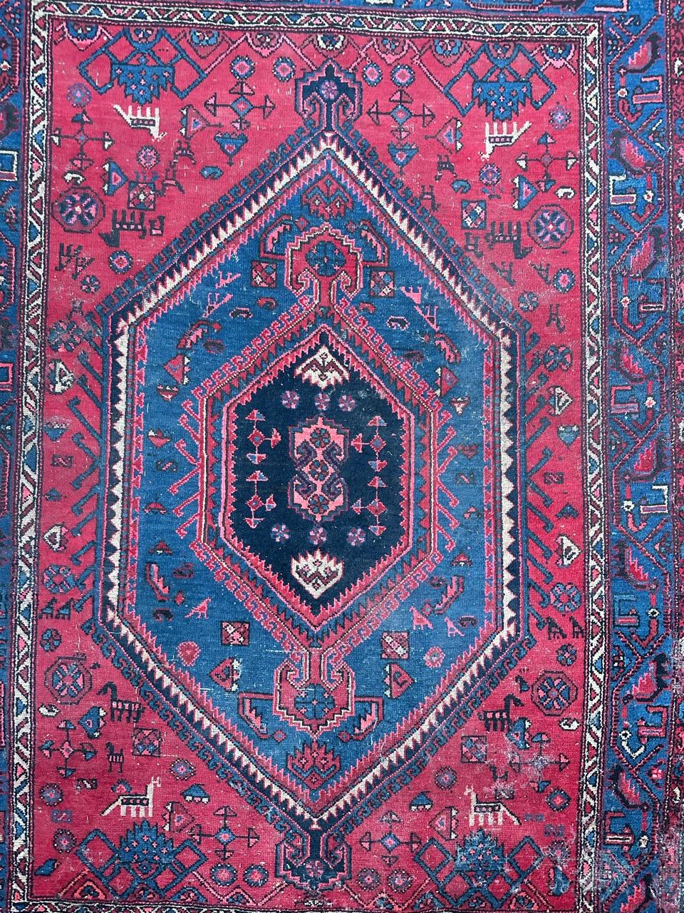 This well-worn Hamadan rug from the mid-20th century is a true testament to its history. Meticulously hand-knotted at home, it boasts a lustrous wool pile on a sturdy cotton foundation. Its rustic charm is highlighted by a striking geometric design,