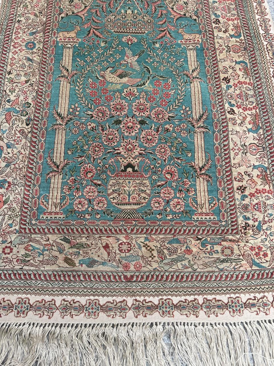 Introducing an exquisite late 20th-century fine silk rug, showcasing a captivating design of birds and flowers. This stunning piece features vibrant colors, including a beautiful green field that serves as the turquoise backdrop for a beige vase