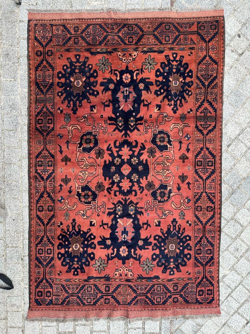 Beautiful Afghan rug from the late 20th century, entirely hand-knotted in wool on a wool foundation. It features stylized and decorative designs on a salmon-red background adorned with dark blue palmettes, stylized crabs, and white arabesques