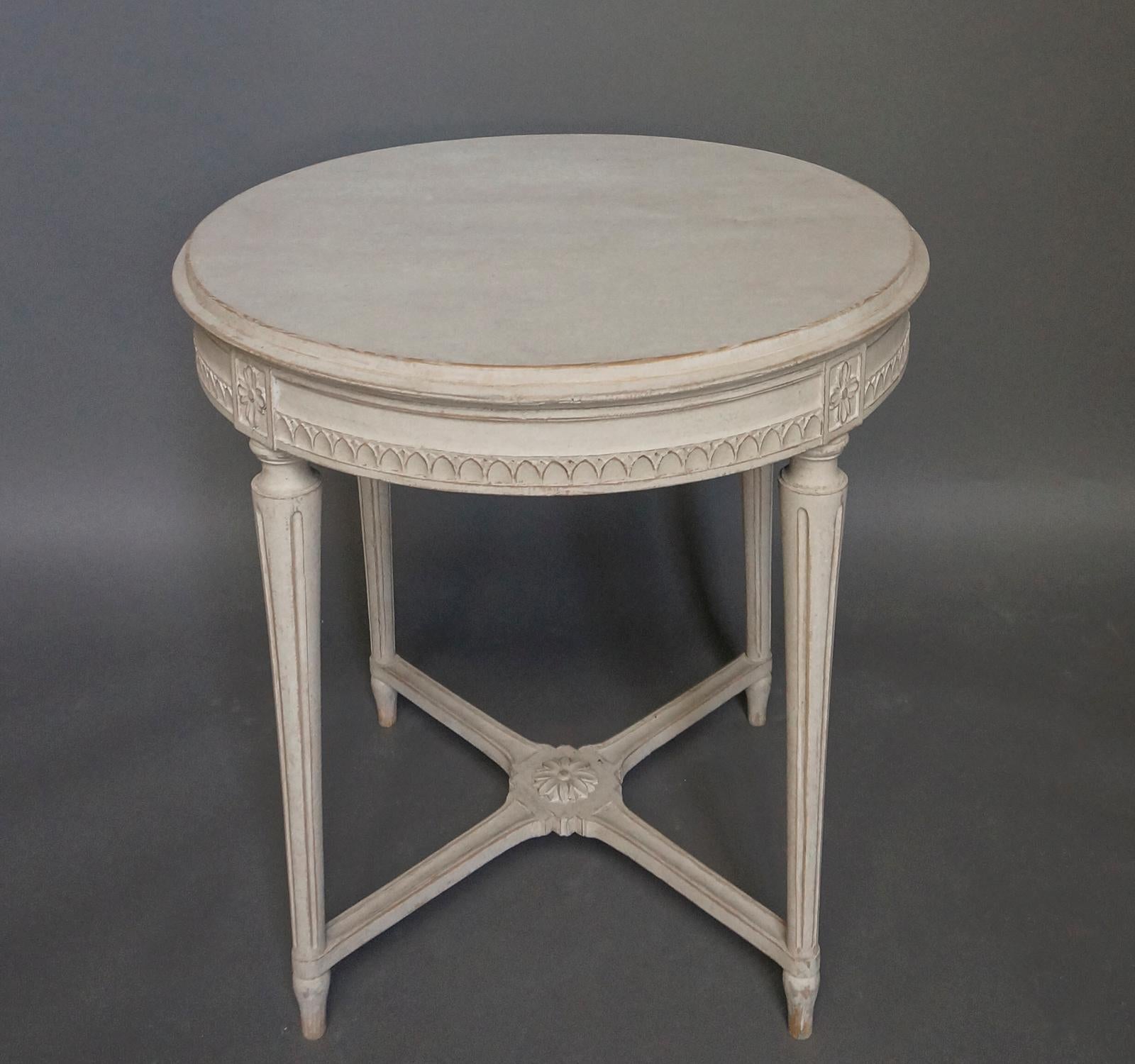 Nicely carved round side table in the Gustavian Style, Sweden, circa 1910. The apron under the shaped top has a border of lamb’s tongue molding between panels with floral detail. The tapering legs are connected with a saltire stretcher with a