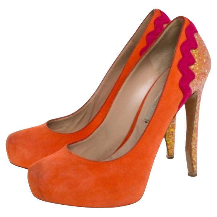 Stand out from a crowd with this gorgeous pair of Nicholas Kirkwood pumps that exude high fashion with class! Crafted from orange suede, this pair comes with round toes and a coarse glitter accents on the counters and heels. Completed with leather