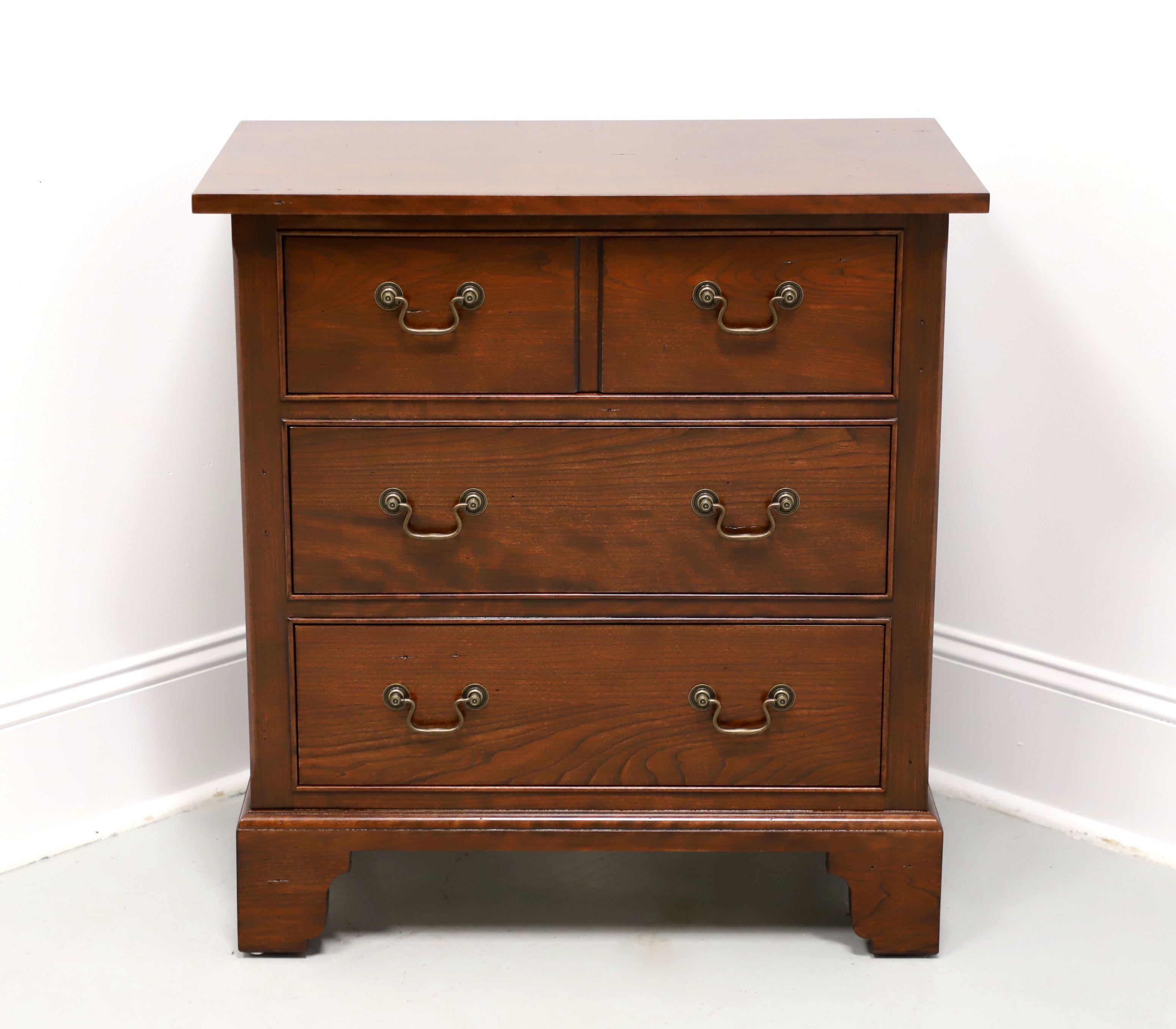 A Chippendale style nightstand by Nichols & Stone, a division of Stickley Furniture, from their Wayside Inn Collection. Cherry wood with brass hardware, flat edge to the top, and bracket feet. Features three drawers of dovetail construction, top
