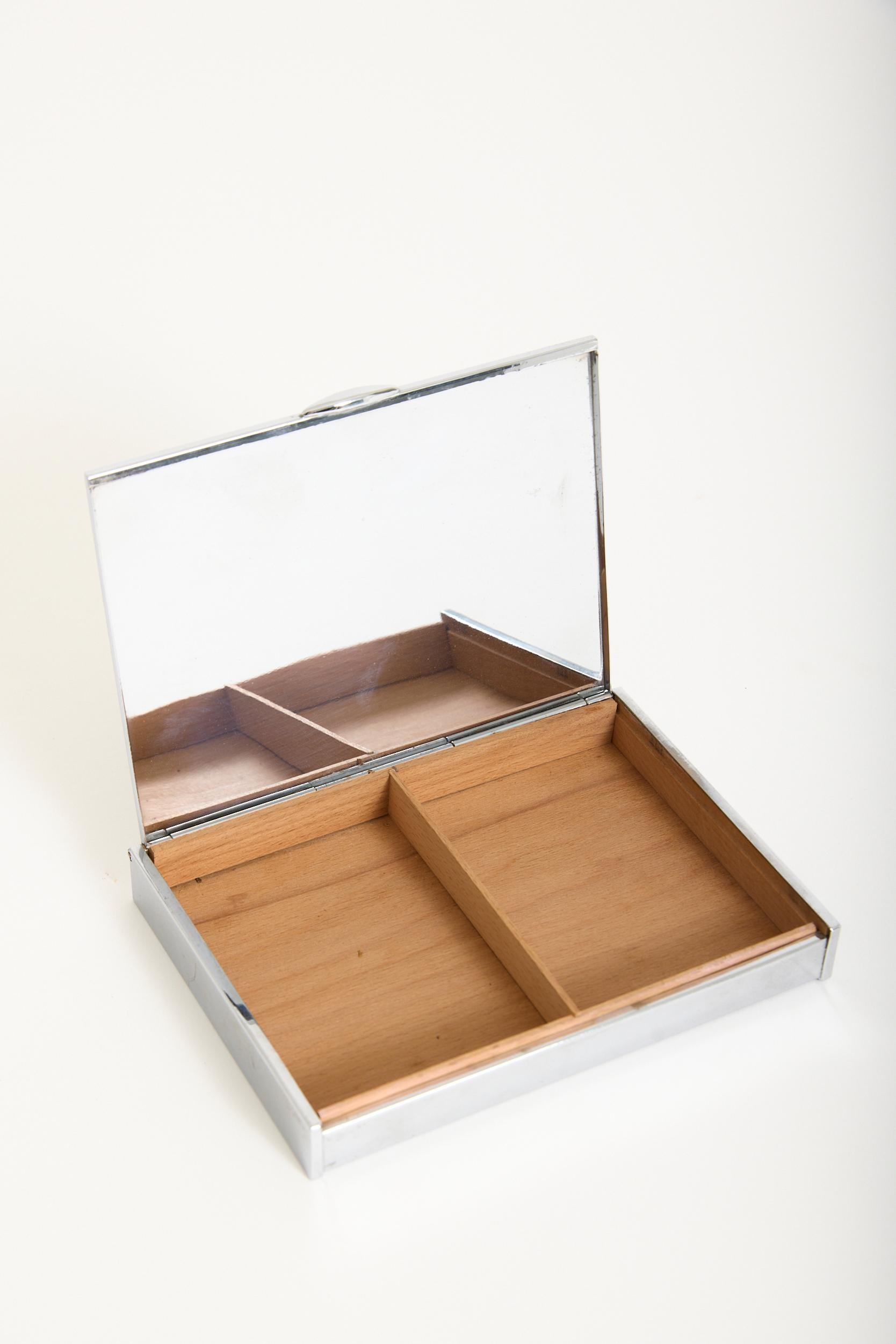A nickel and black enamelled box, with a mirrored interior
France, mid 20th Century
