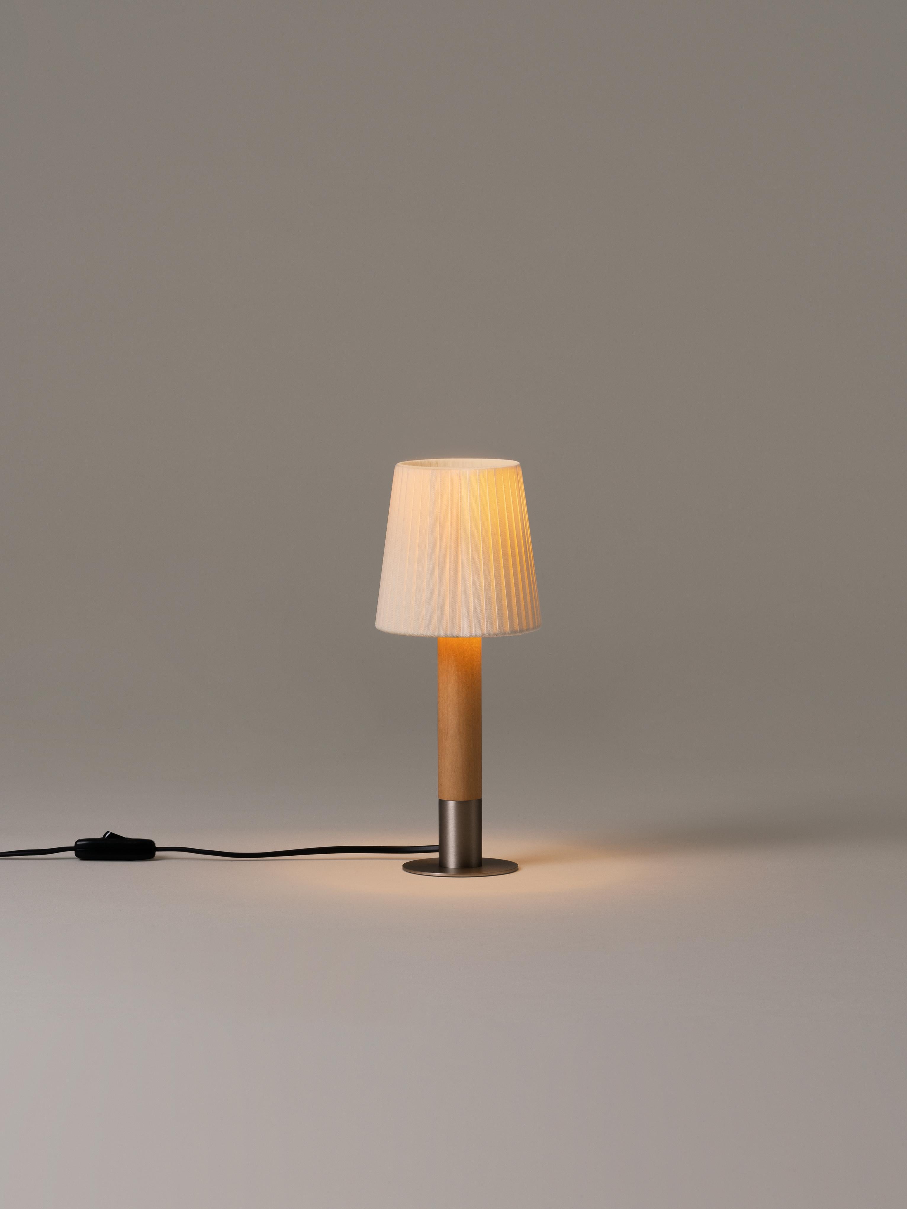 Nickel Básica Mínima table lamp by Santiago Roqueta, Santa & Cole.
Dimensions: D 12 x H 30 cm.
Materials: Nickel, birch wood, ribbon.

Básica Mínima is the pocket edition of the Básica lamp. On its own or with others, it combines sturdiness and
