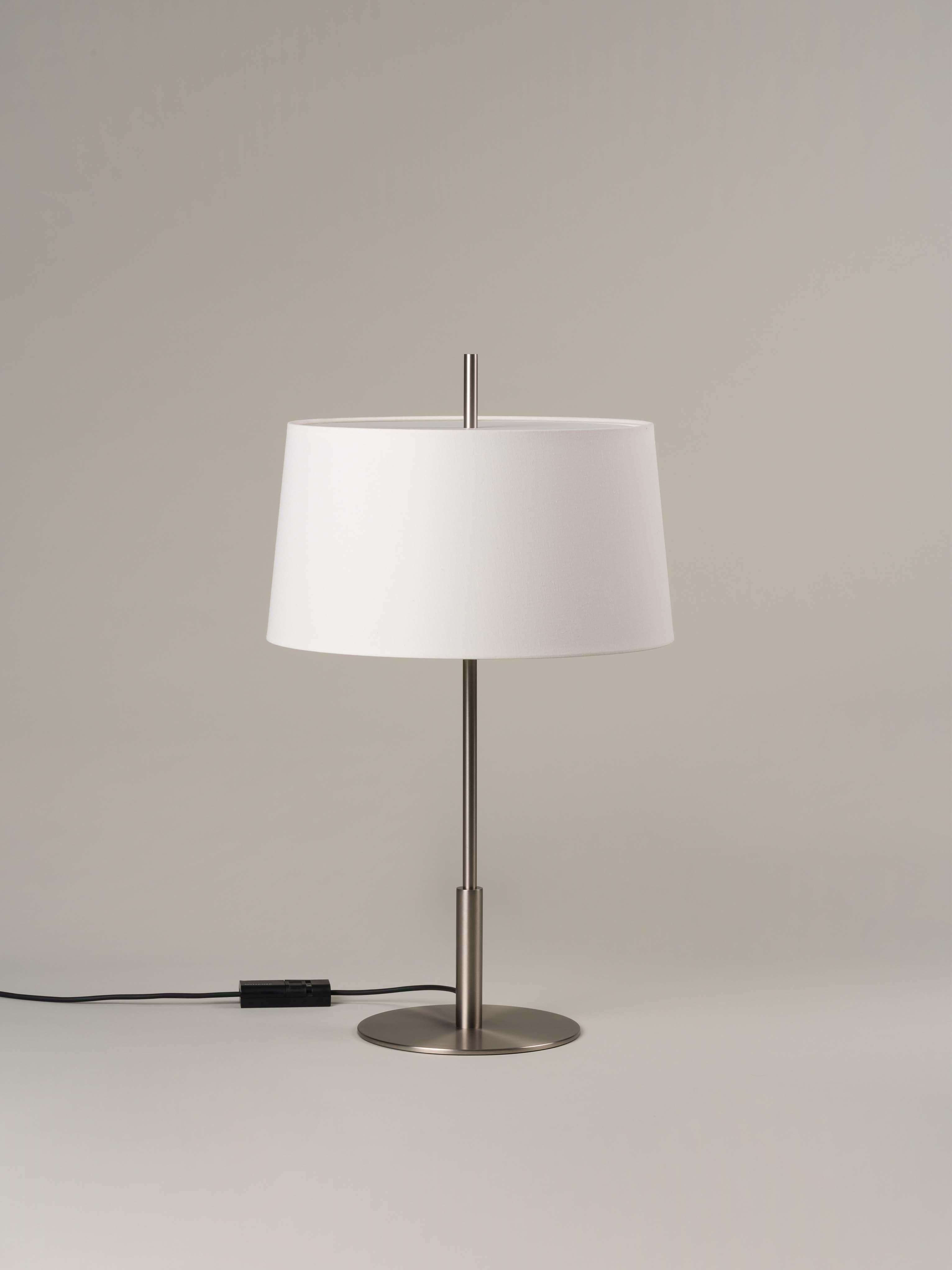 Lampe de table Diana en nickel par Federico Correa, Alfonso Milá, Miguel Milá
Dimensions : D 45 x H 78 cm
Matériaux : Lin blanc, nickel.
Disponible en abat-jour noir ou blanc et en finition or ou nickel.

Conformément à la vocation de ses créateurs,