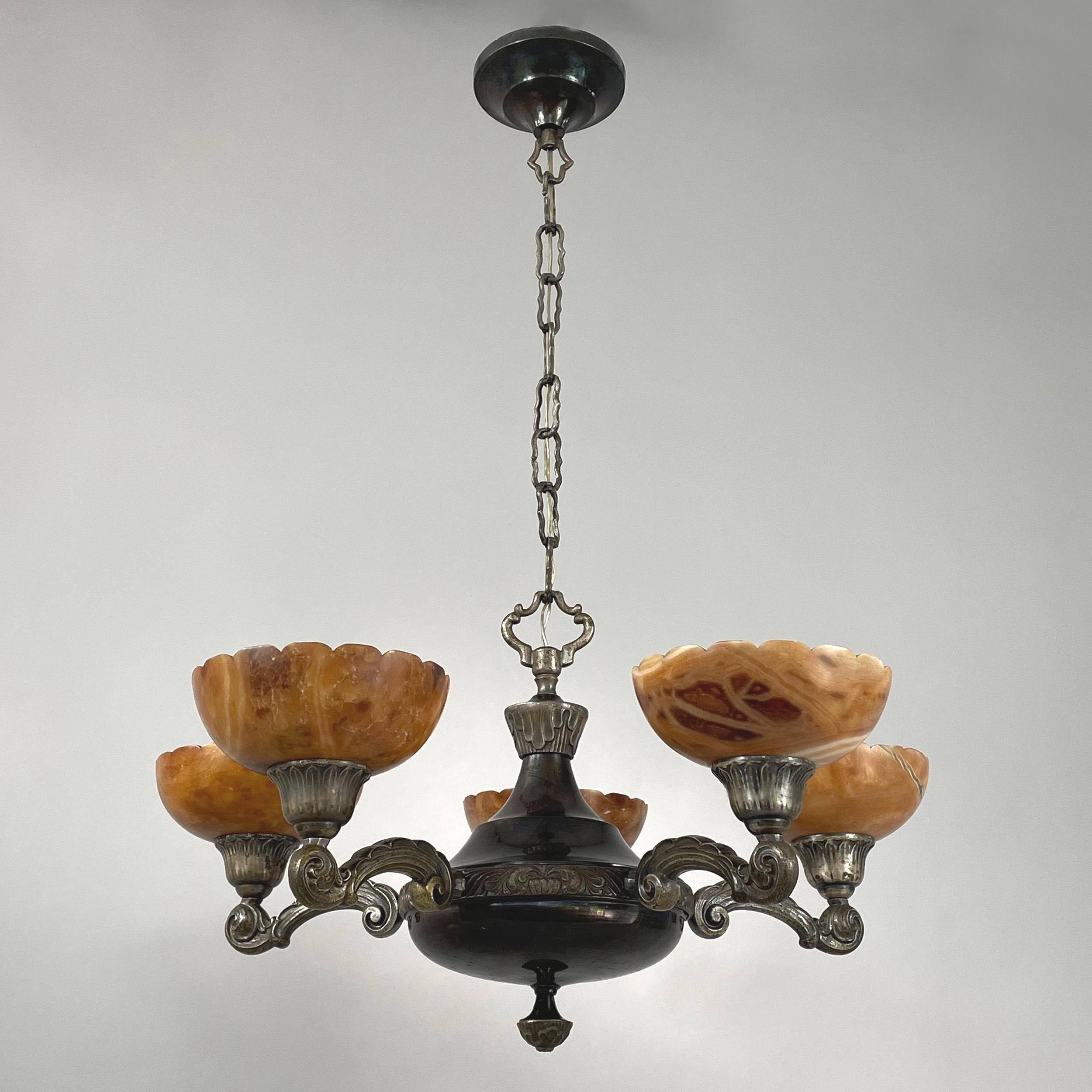 Lustre Art-Déco à 5 lumières d'un designer suédois, années 1920-1930.

Ce lustre impressionnant présente un cadre en laiton nickelé avec des détails complexes et des abat-jours en albâtre de couleur chaude ambre / caramel dans un design festonné.