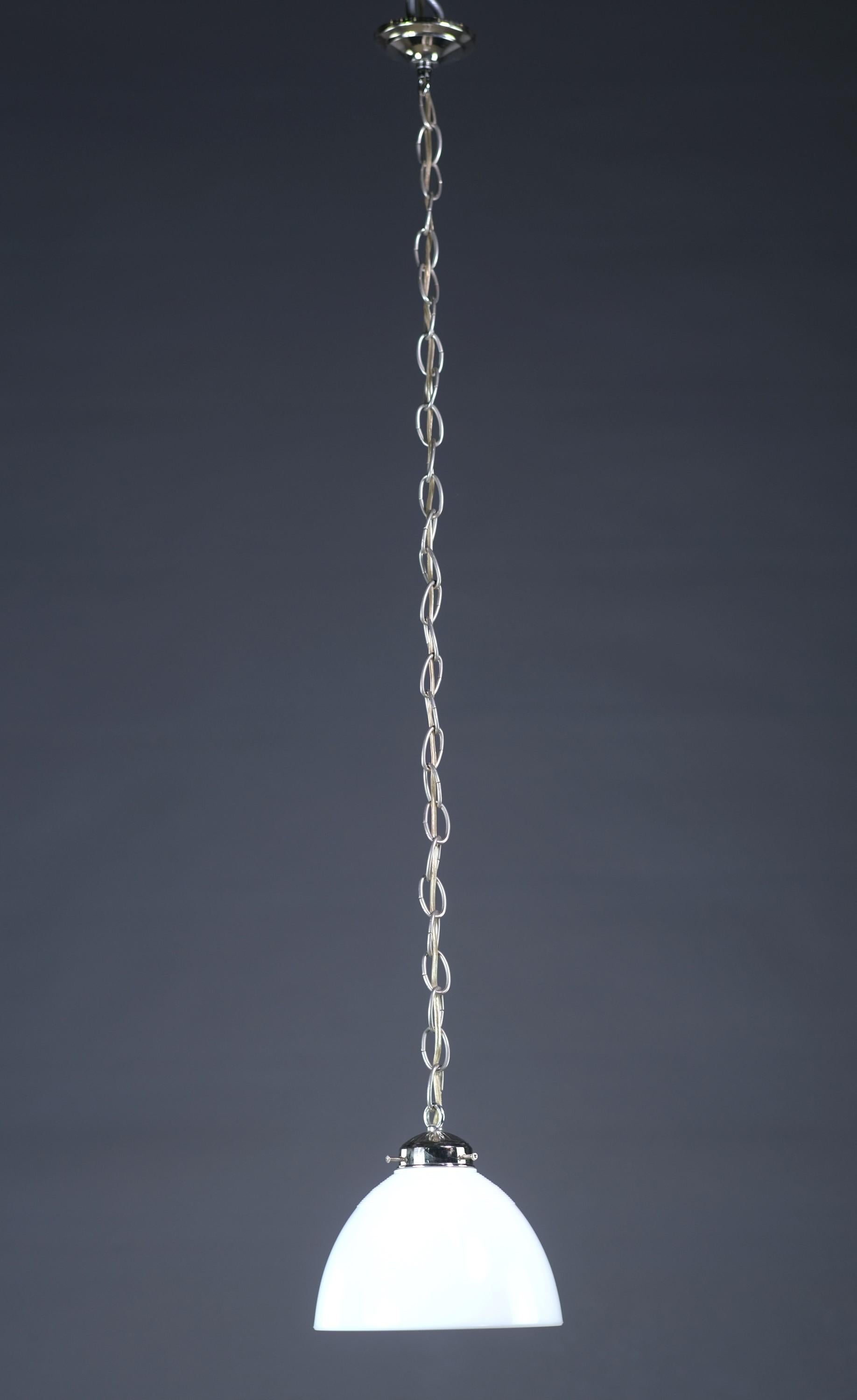Lampada a sospensione del XX secolo. Presenta una ferramenta placcata in nichel e un paralume bianco con un design a coste nella parte superiore. È necessaria una lampadina domestica E26.