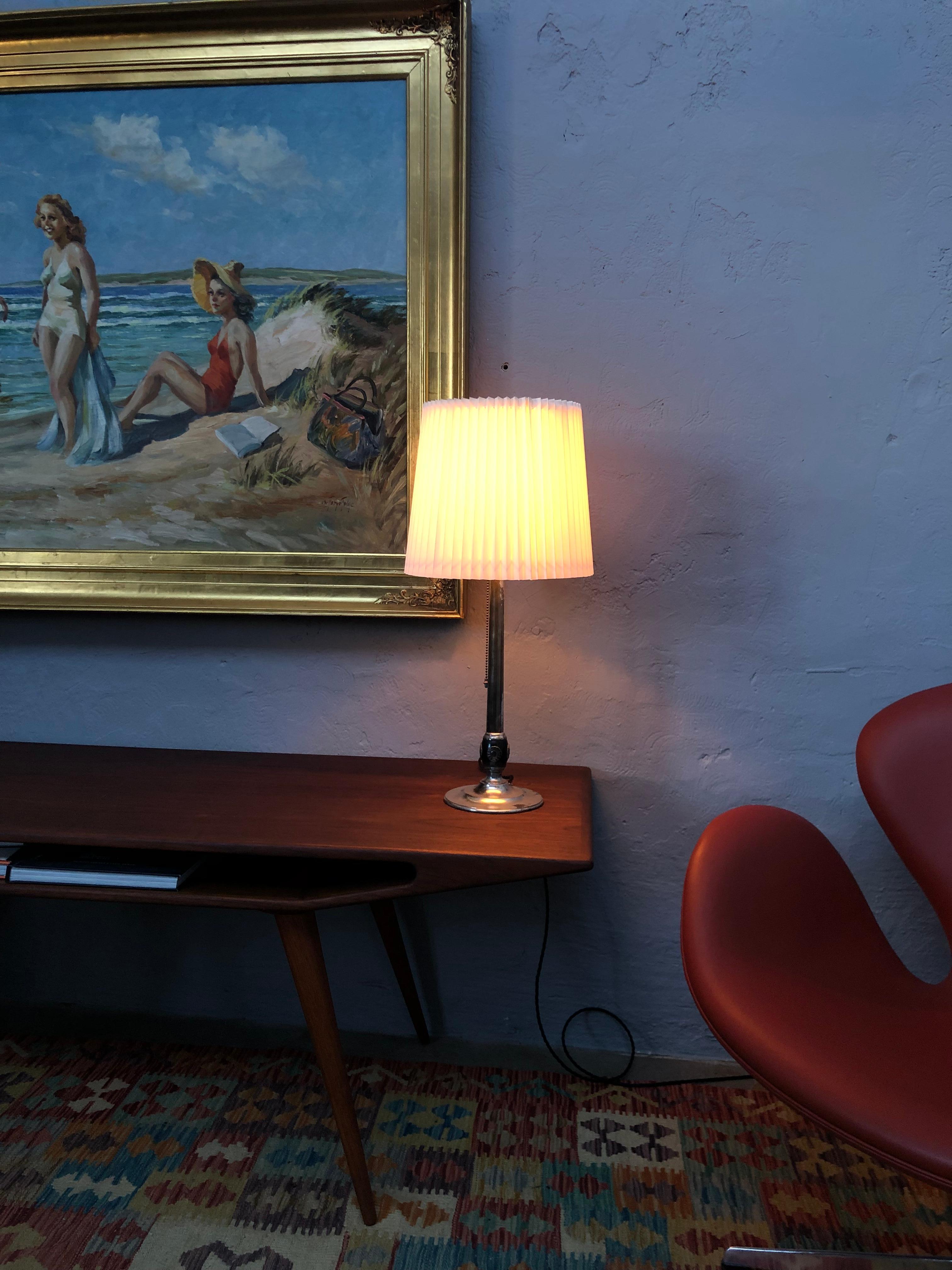 Lampe de table suédoise Art Nouveau en maillechort des années 1920. 
Une base ronde pressée et une tige avec une base boule munie de 4 volants pétrifiés en argent. 
Estampillé sur la base 