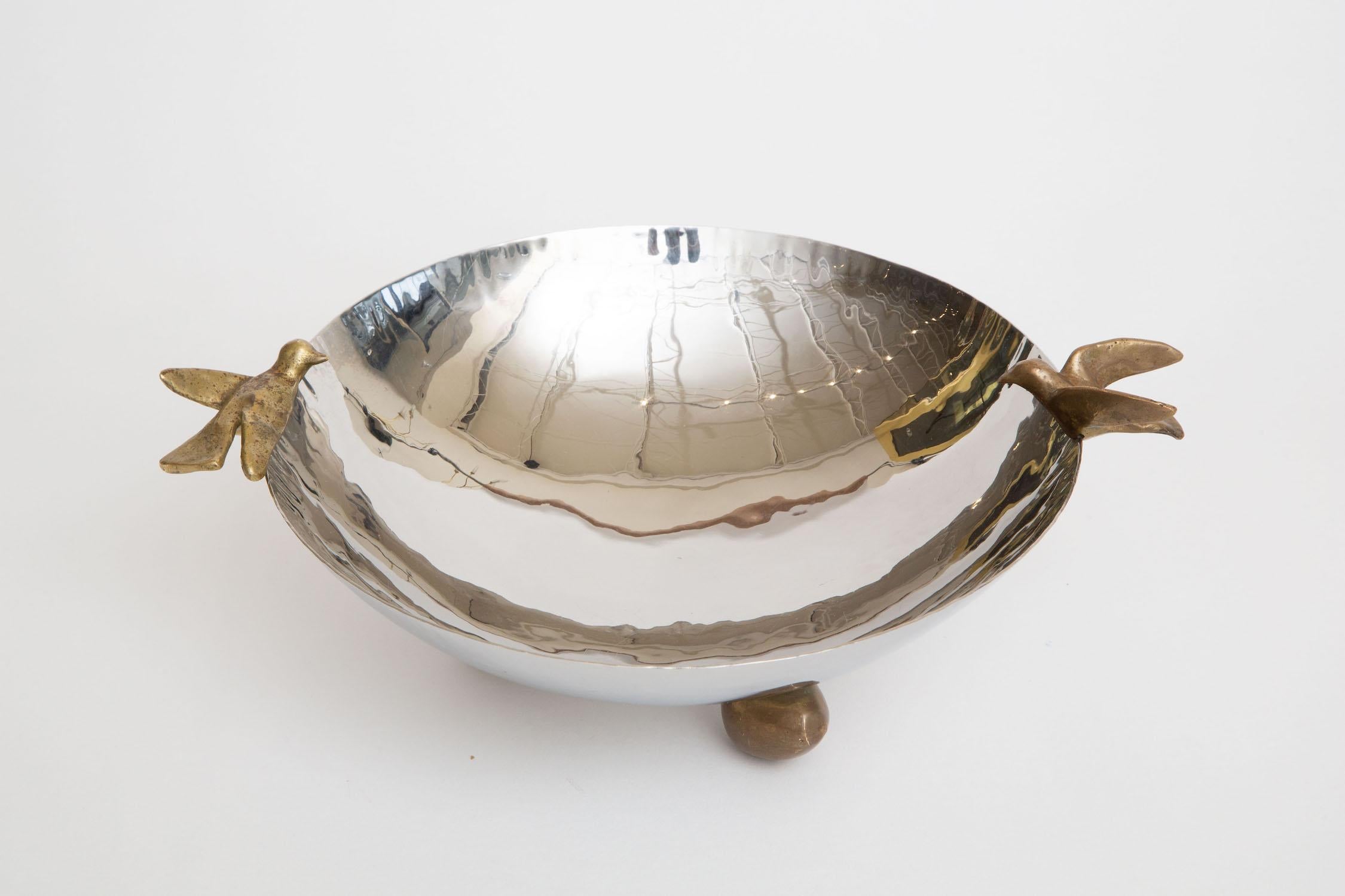 This lovely bowl or serving bowl has brass dove birds on either side and 3 rounded brass ball feet. It is not marked anywhere of the maker. It is from the 80's. it is a combination 2 part metal of nickel silver and brass. it is best for serving for