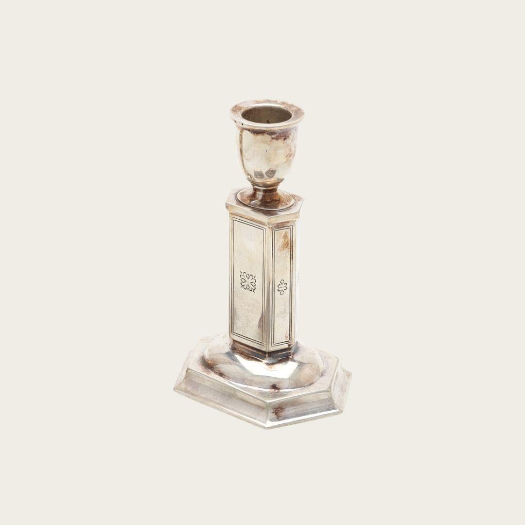 1940s, Sweden. Candle holders feature a classic Art Deco design with a column shape, octagonal footed base, and detailed floral engraving. Crafted from nickel silver, they show a significant patina that highlights their age and authenticity. Each
