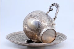 Nickel silver cup and saucer with floral engravings and monogram panel