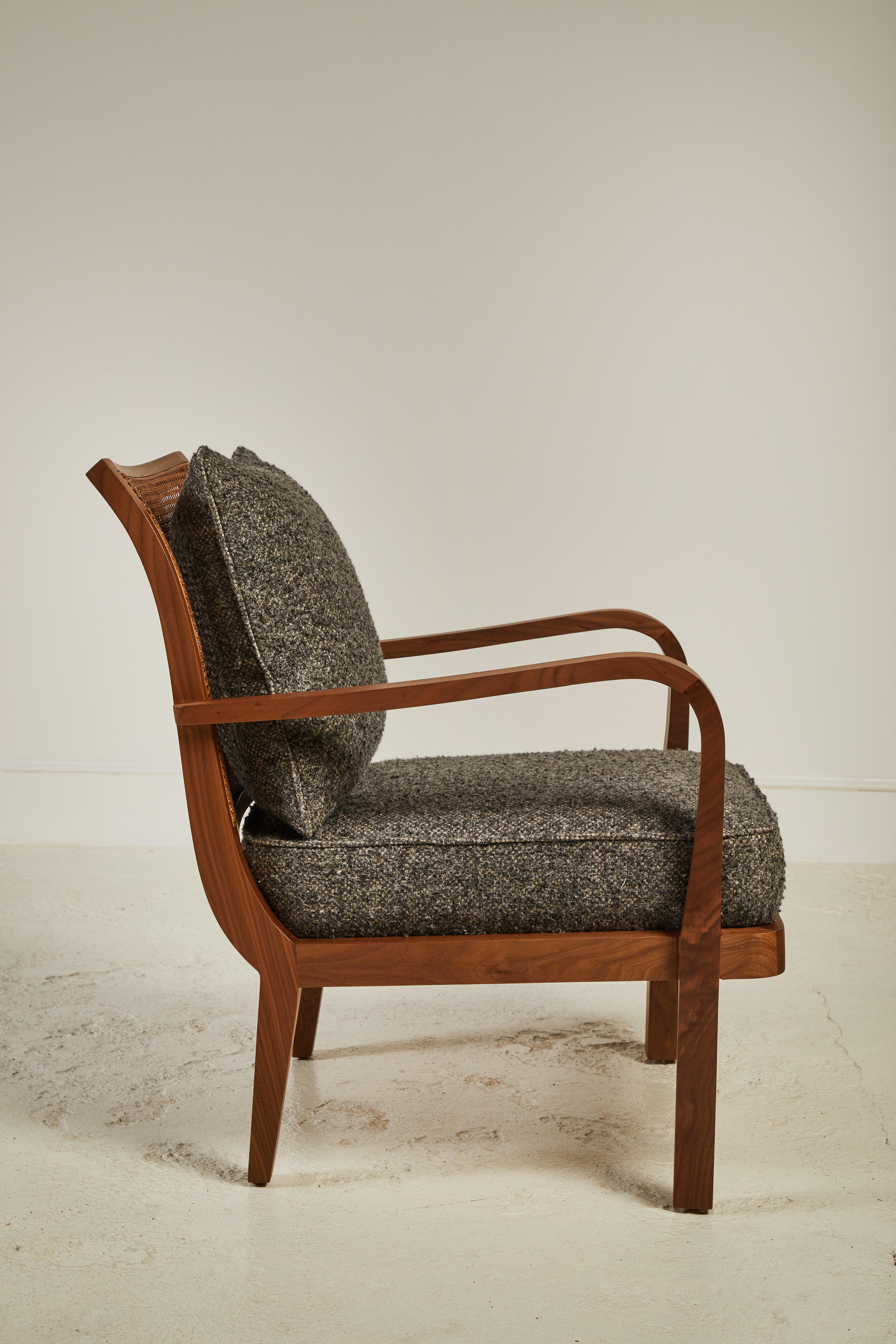 Nickey Kehoe collection cane back chair is a spin on the classic occasion chair. The chair sits upright with a comfortable tight seat and loose back cushion. The chair is constructed in walnut wood, and has a beautiful caned back. This specific