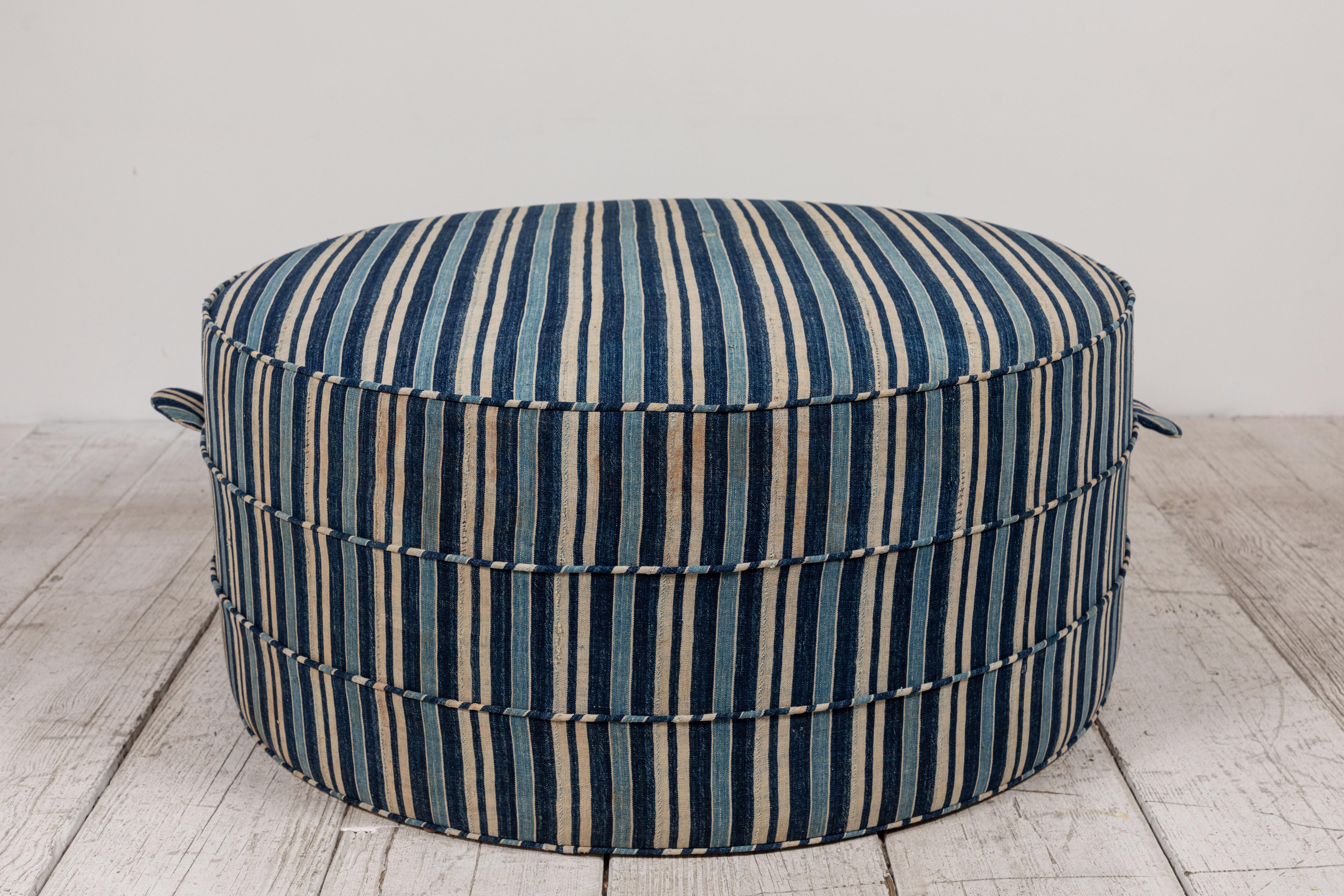 Solid wood frame and upholstered hassock with two ring piping and double handle details offers versatility in accent seating. This specific hassock is upholstered in a one of a kind Striped Indigo textile from Burkino Faso.