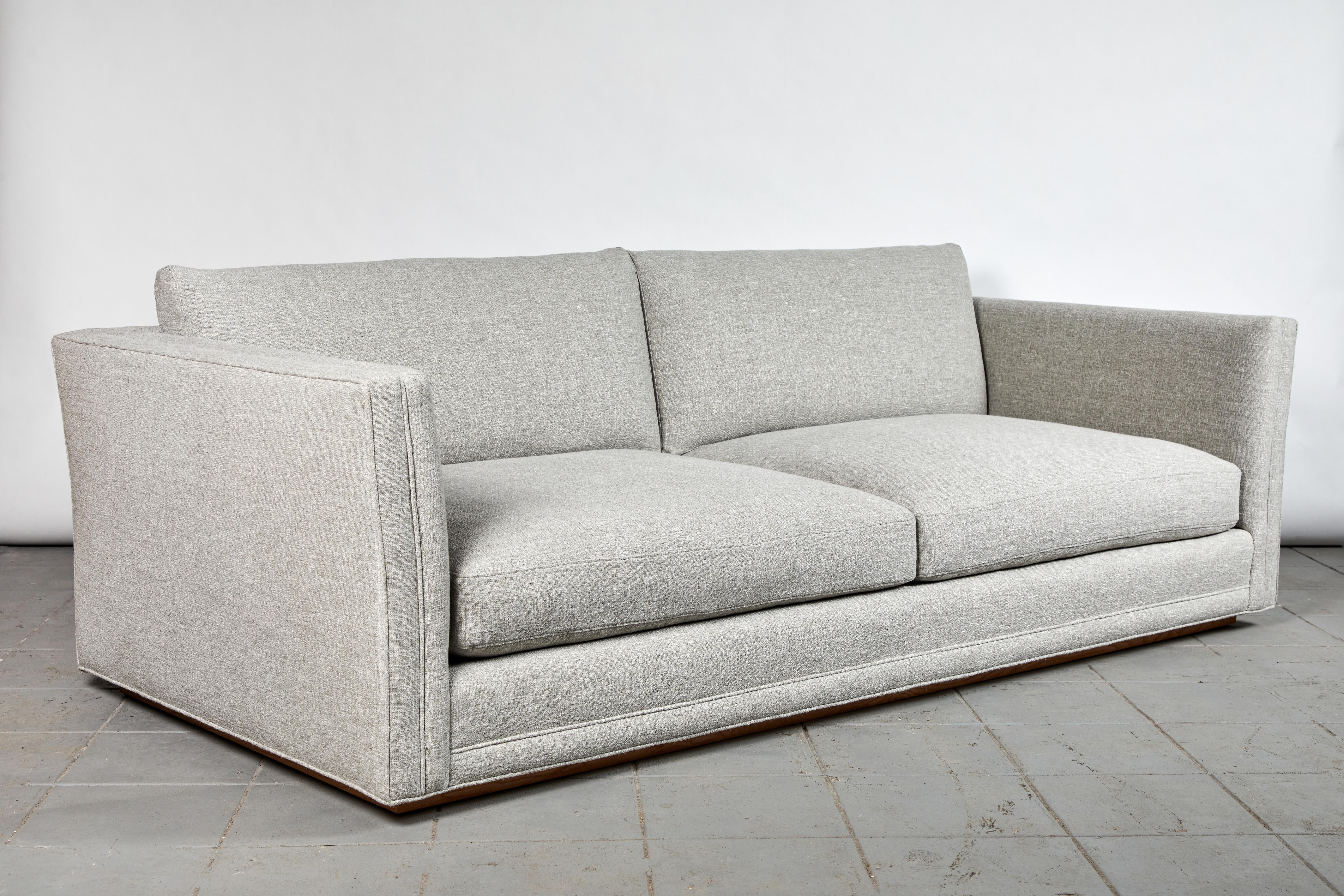 The double welt and slight fare to the modern lounge sofa make it a distinct, Classic piece. Its generous depth adds to the comfort of the down-encase foam inserts. Solid frame, hand-tied springs, and recessed solid walnut plinth shadow base present