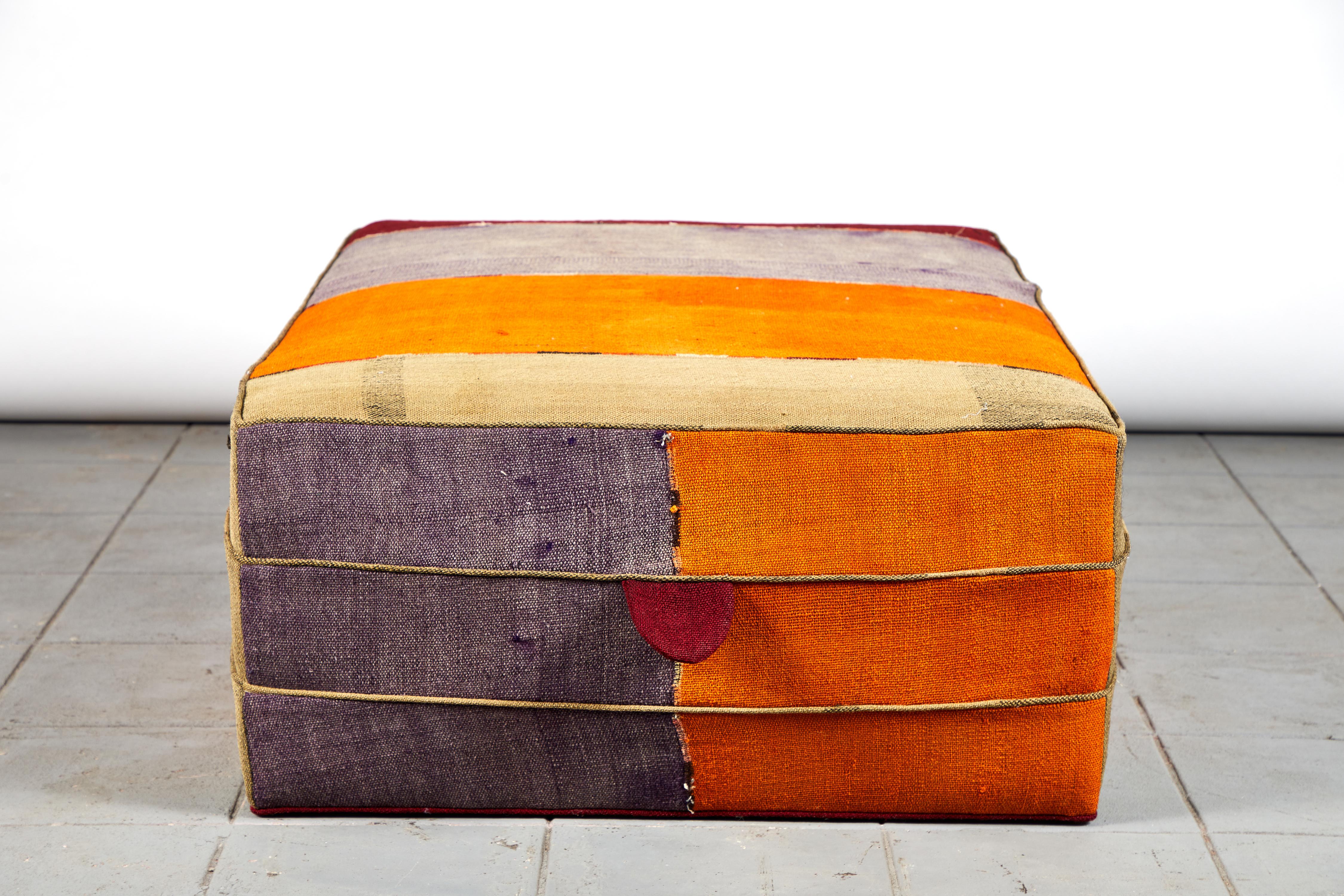 Nickey Kehoe collection rectangular ottoman in vintage Turkish colorful fabric with vibrant shades of orange, red, green and violet.
  