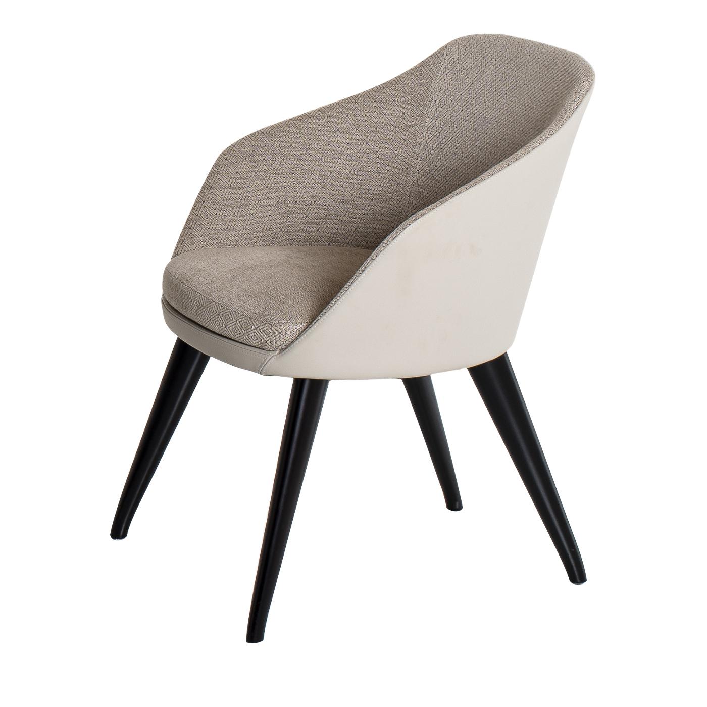 The contemporary design dove-grey Nicki chair is characterized by the combination of leather and fabric and is supported by four long angled tapered metal legs lacquered in black. This chair is versatile and easy to combine with other elements in a