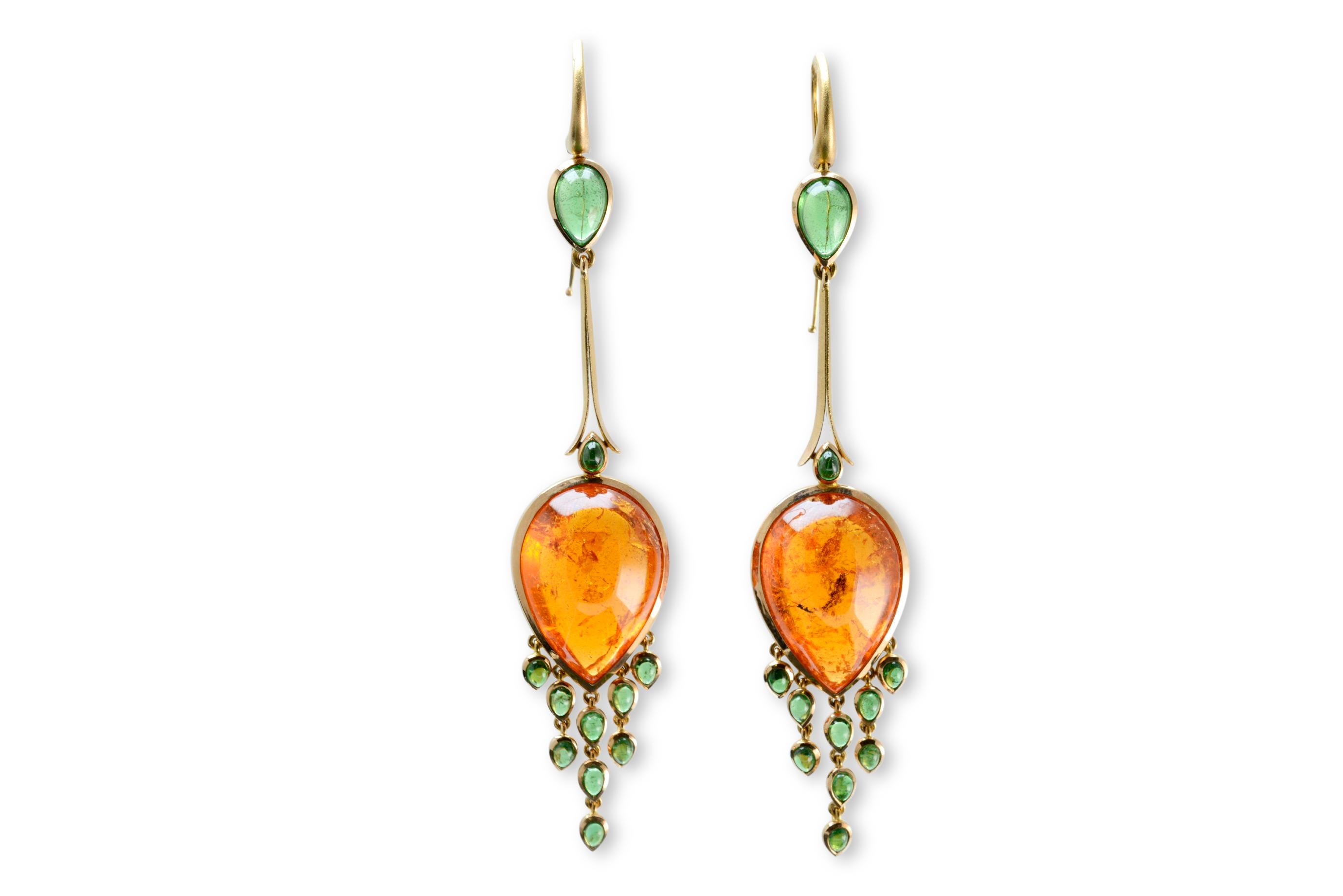 Hand picked for their luminous beauty is a pair of pear shaped mandarin garnets. They have been delicately framed in handmade 18 carat rose gold bezels. Specially cut pear shaped tsavorite garnets form tassels that dangle from the bottom. An