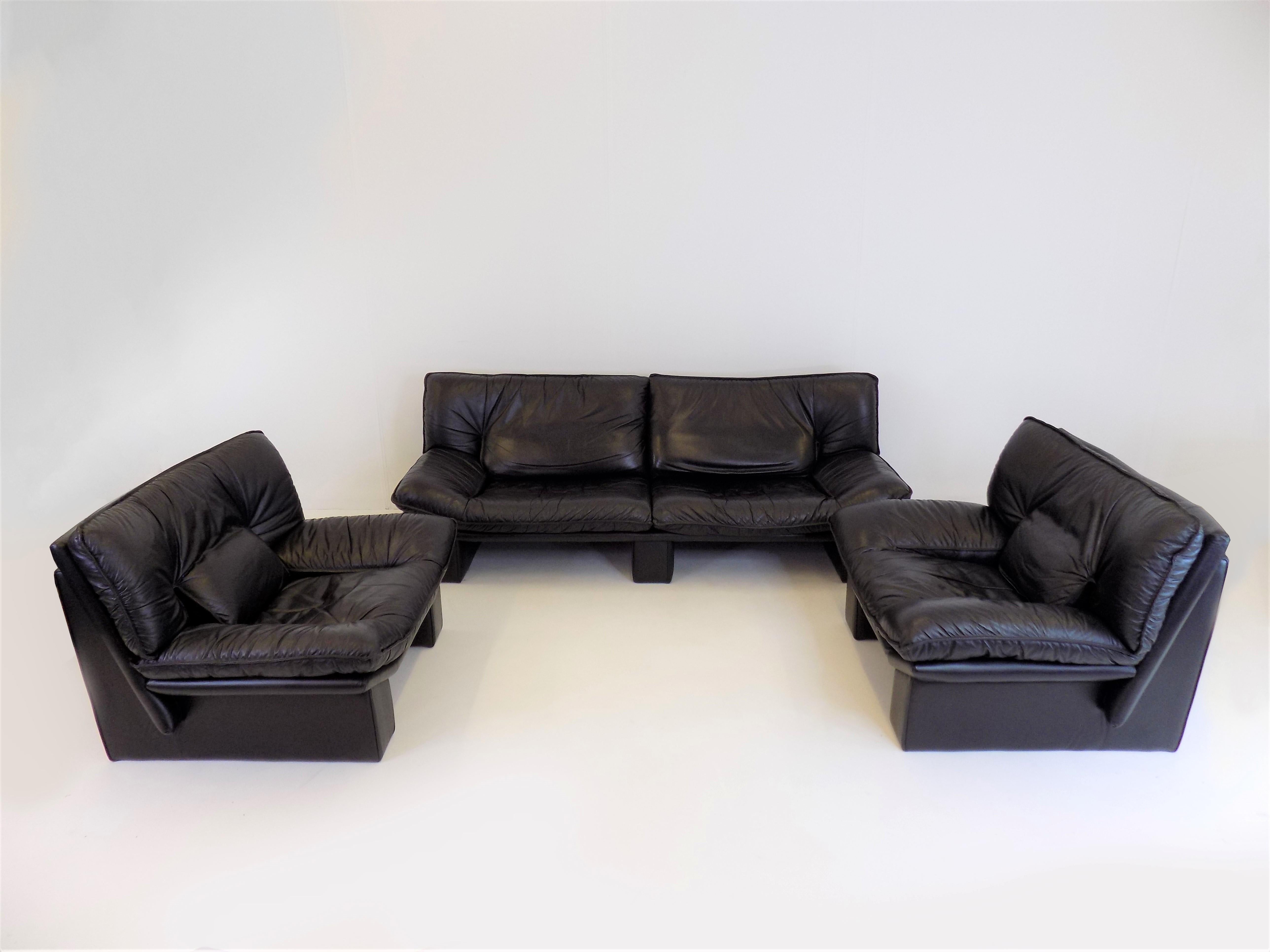 The living room set consists of a 3 seater sofa and 2 armchairs upholstered in black leather. The soft leather of the armchairs and the sofa is in excellent condition and shows minimal signs of wear. This model by Salotti is characterized by the
