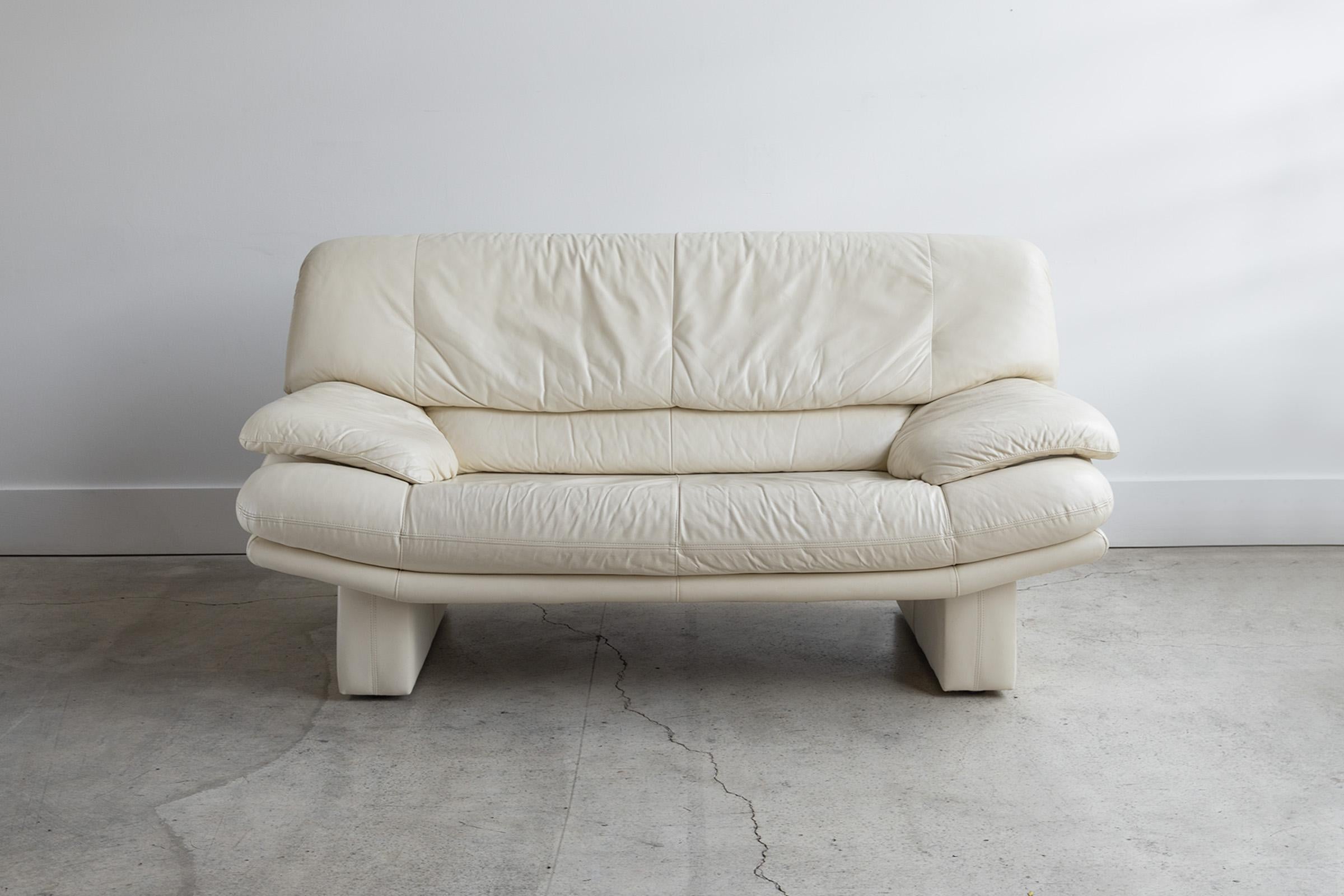 Sink in and feel like you're on a cloud with this stunning postmodern Nicoletti Salotti Italian leather loveseat in a gorgeous off-white cream. A statement piece in your living room or anywhere you decide to put it. Would pair nicely with modern