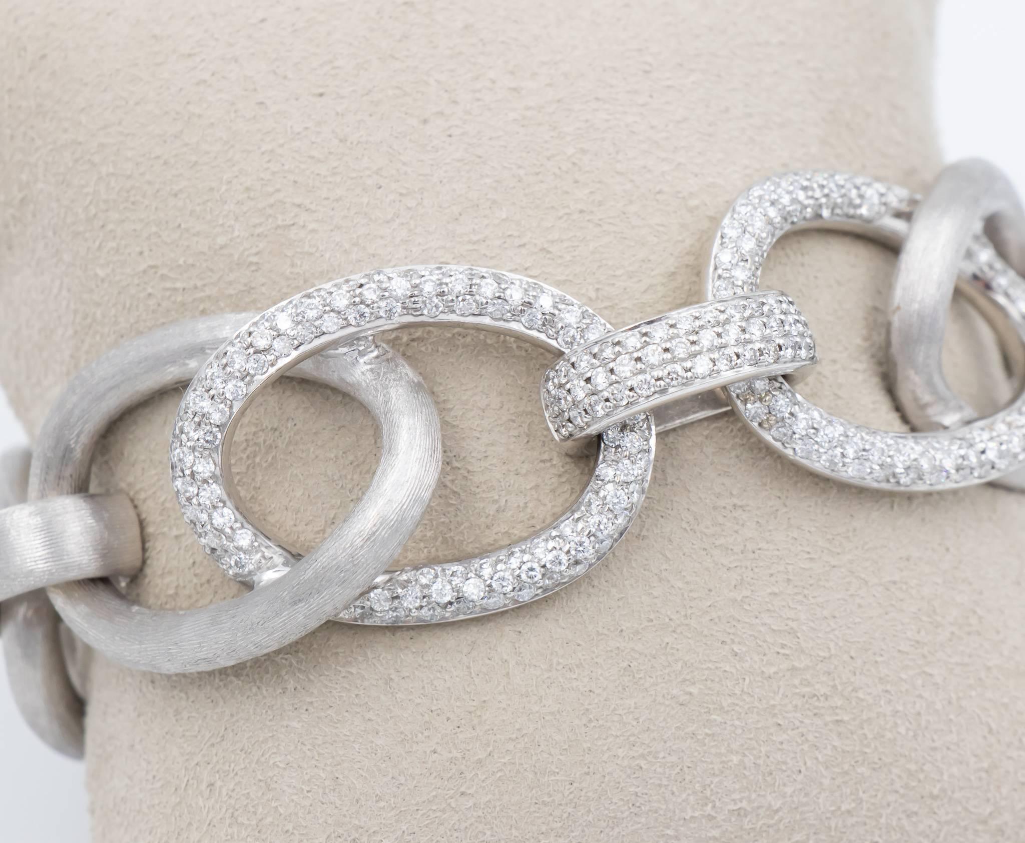 This link bracelet showpiece has a large link style with approximately 3.00 carats of high quality round brilliant diamonds.  The diamonds are pave set on three of the stations.  This is a finely made bracelet in 18k white gold with a hand engraved