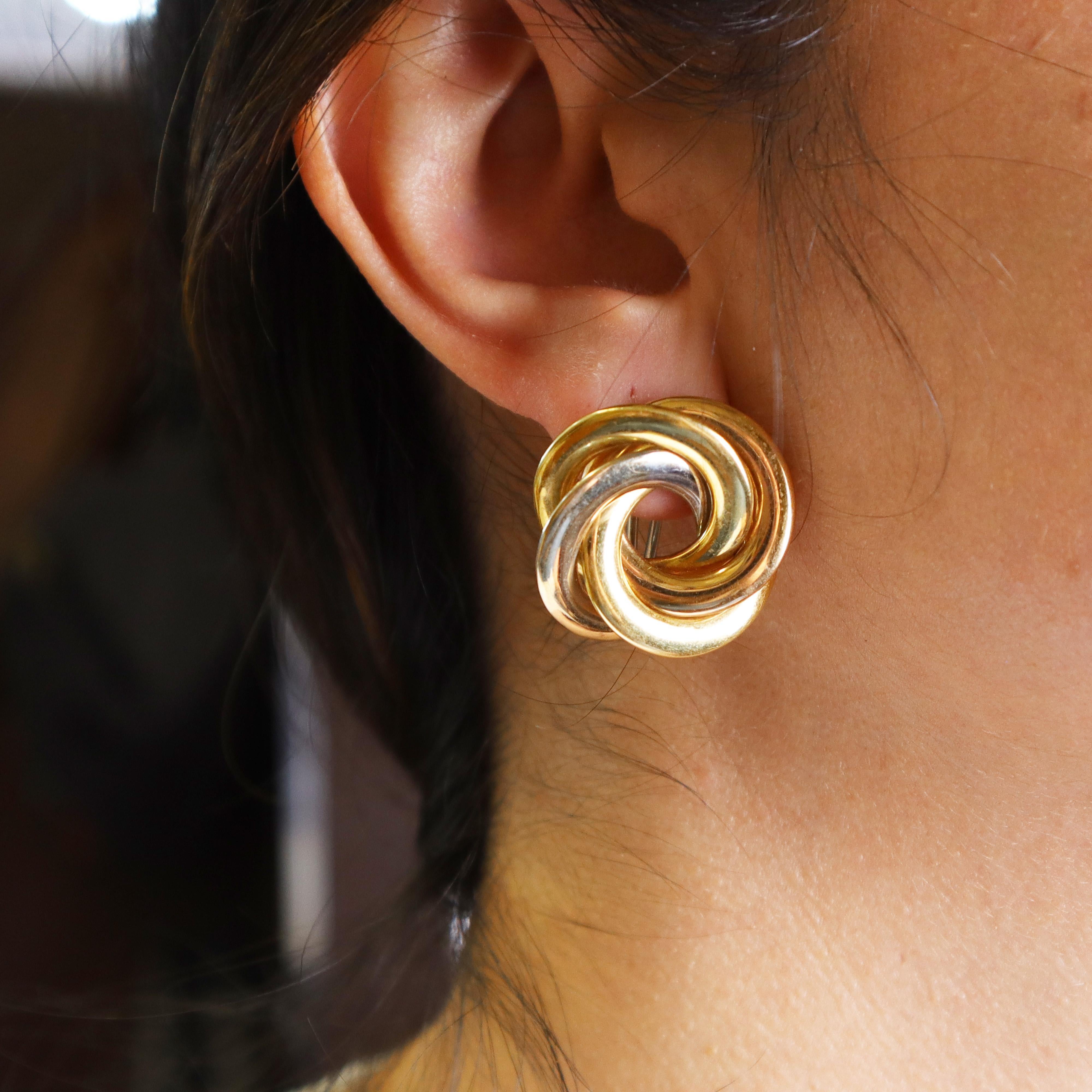 Die Lovers Knot Earrings sind eine atemberaubende Kreation des renommierten Designers Nicolis Cola, die meisterhaft aus einer harmonischen Mischung aus 18-karätigem Gelb-, Rosé- und Weißgold gefertigt ist. Diese Ohrringe verkörpern eine romantische