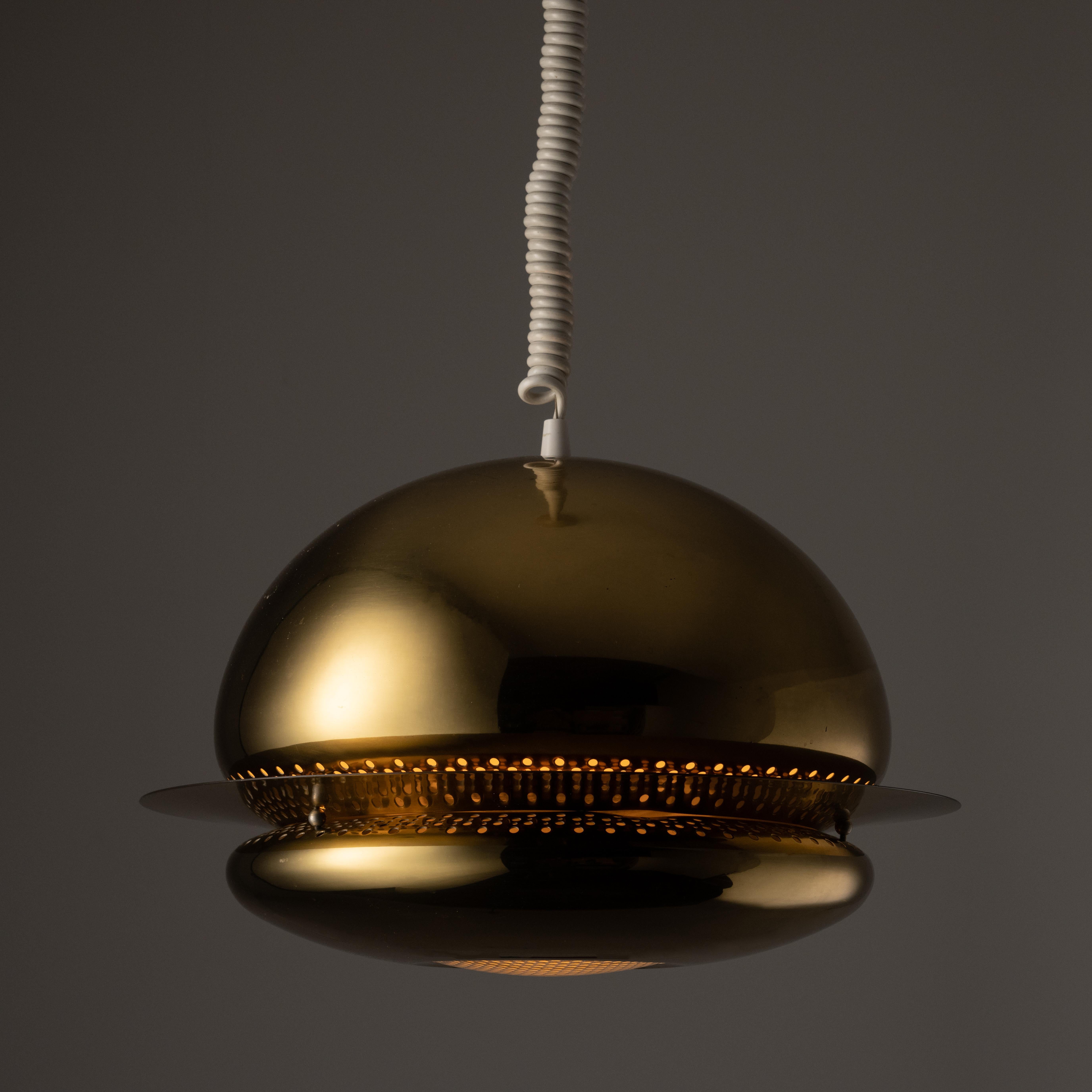 Nictea pendant by Afra and Tobia Scarpa for Flos. A cloud like all polished brass pendant featuring a bulbous top and bottom shade, sandwiched in-between a perforated brass ring. The ring allows for a beautiful starry illumination towards the