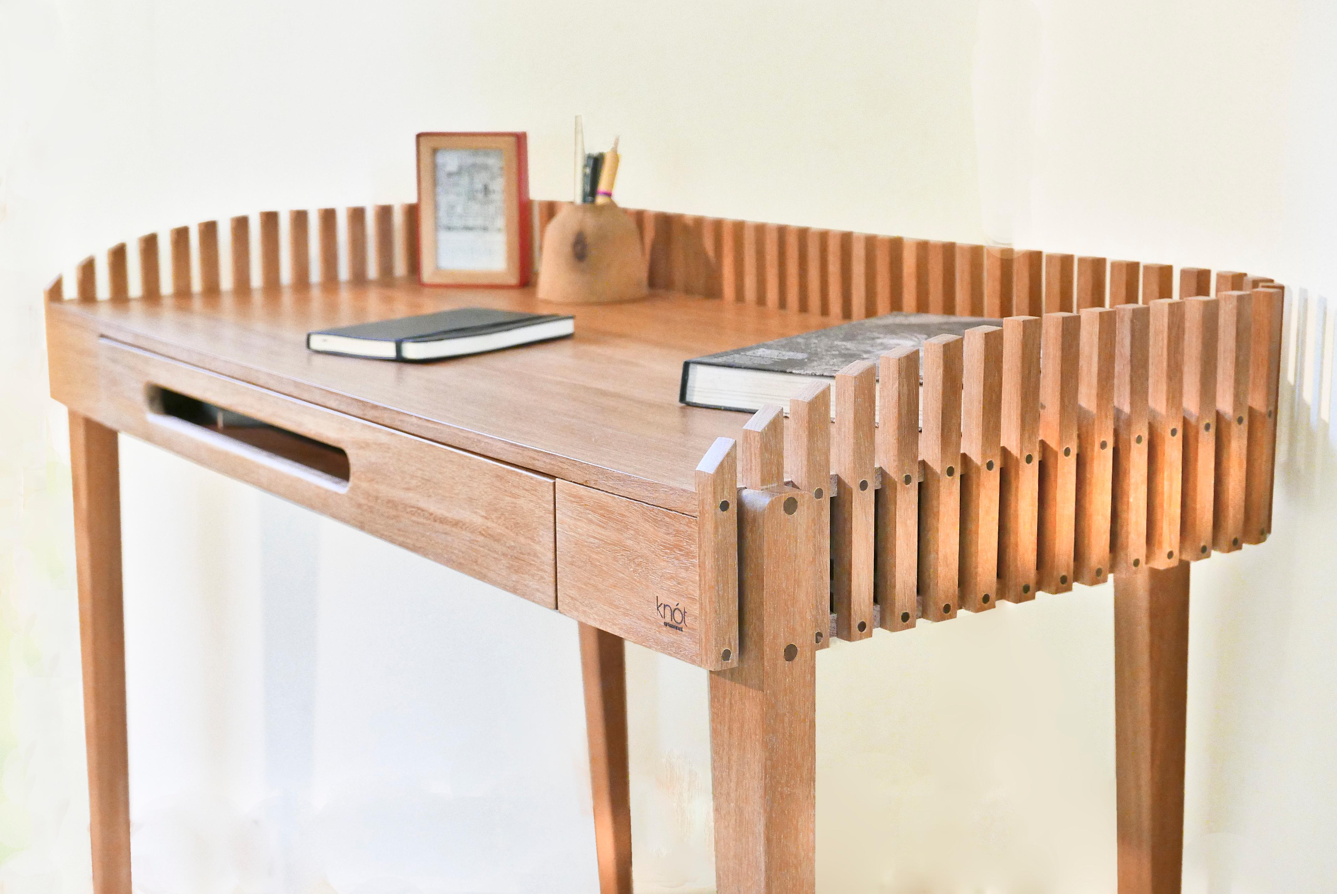 Der Schreibtisch Nido besteht aus einer großzügigen Arbeitsfläche und einer schlanken Schublade, die von zarten Lamellen umschlossen wird und auf vier schlanken Beinen ruht. Der versetzte Schubladengriff unterbricht die Symmetrie des ansonsten