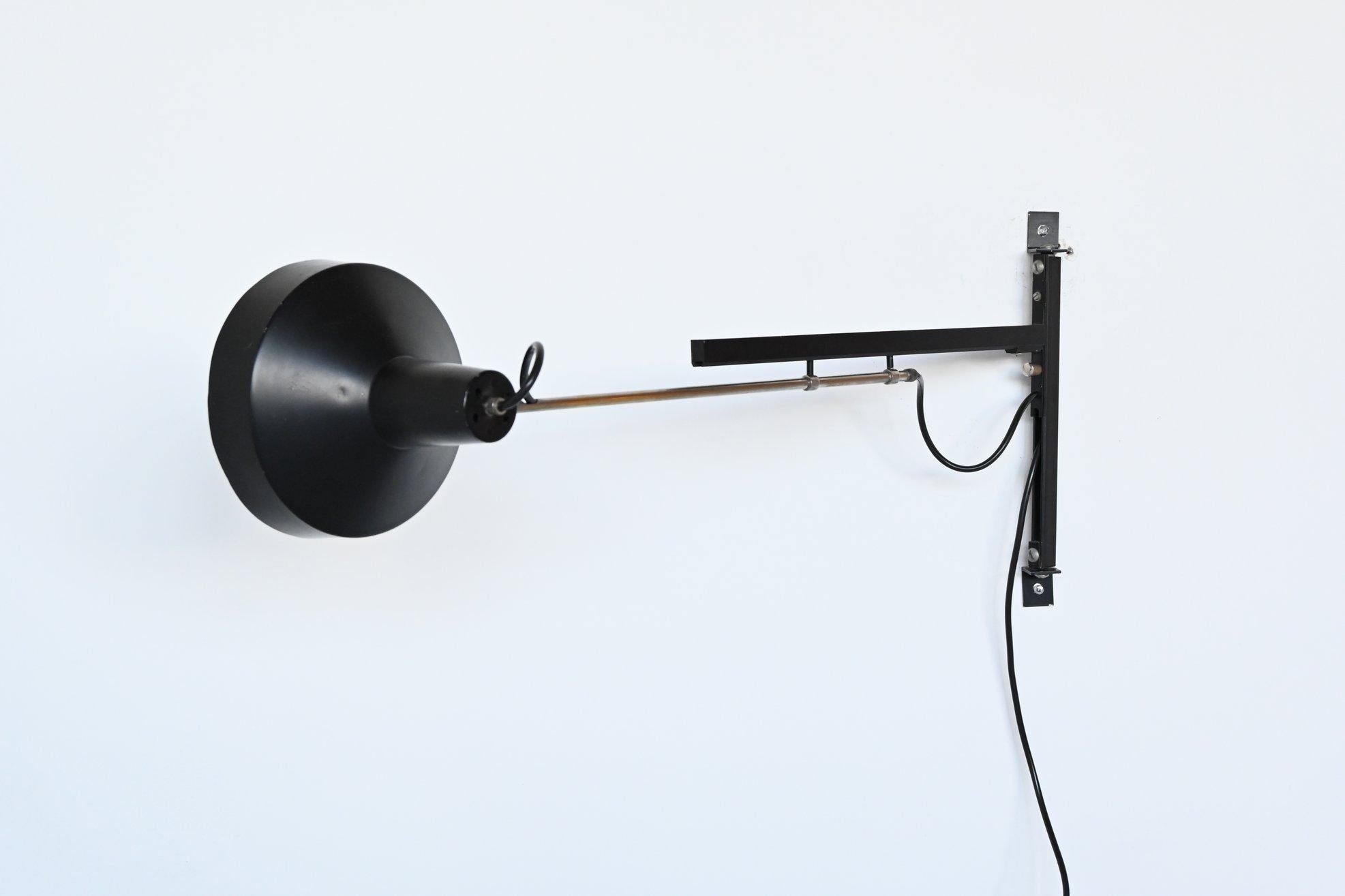 Very nice adjustable telescope wall lamp designed by Niek Hiemstra for Hiemstra Evolux, the Netherlands, 1960. It has a nickel arm and black lacquered shade and details. This multi-adjustable wall lamp is easy adjustable in almost every conceivable