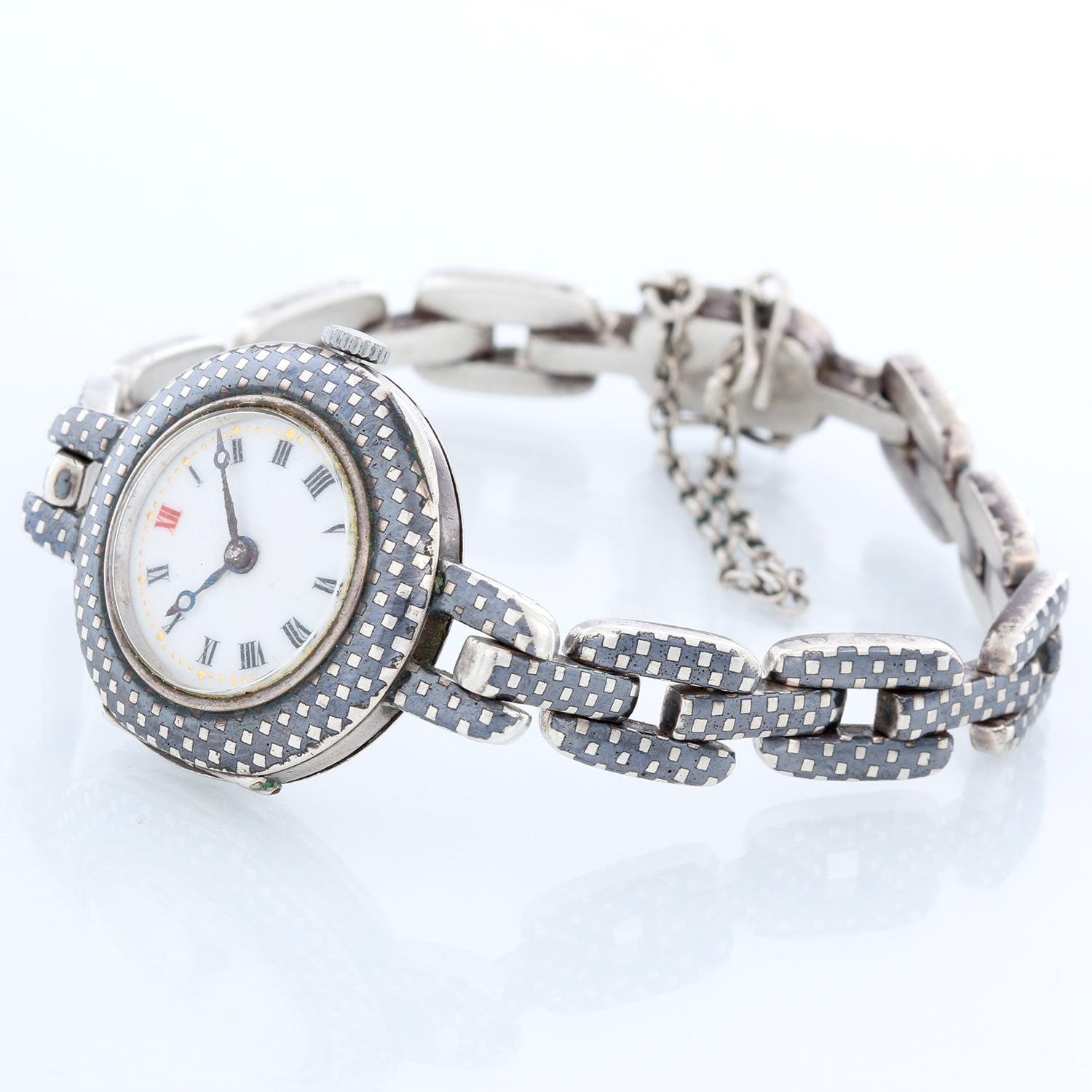 Niello Ladies Manual Winding Wrist Watch - Manual. Steel case with checkered Niello pattern ( 26 mm) . White dial with Roman numerals. Niello checkered link bracelet; fits a 7 1/4 inch wrist. Pre-owned with custom box. 

Please allow 10 days for a