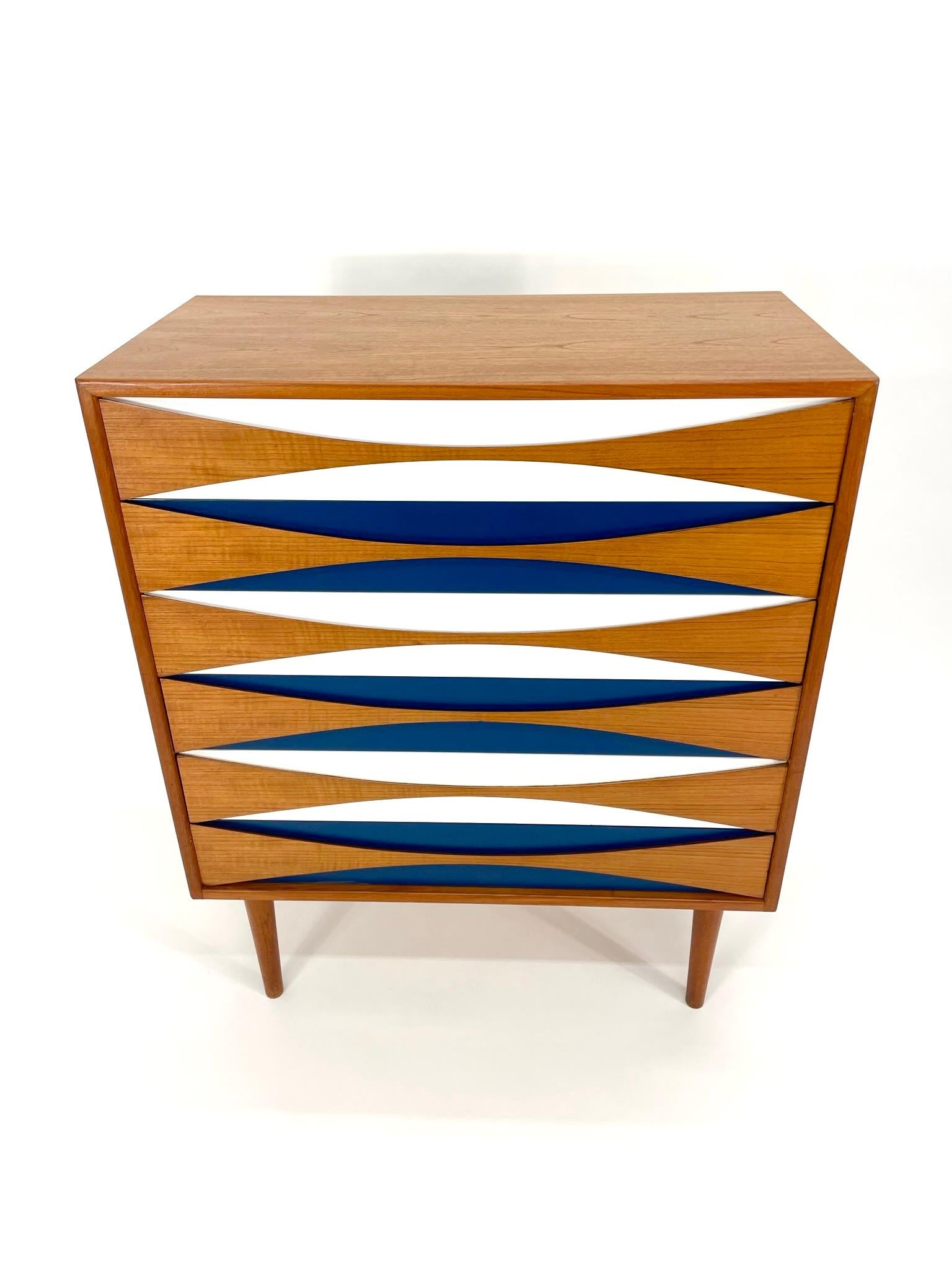 Niels Clausen Teak and Oak Tallboy Dresser with Blue and White, circa 1960s. Features sculpted “Bow tie” front drawers made of teak with solid teak drawers and blue and white paint to add a pop of color. Colorful furniture pieces became a staple in
