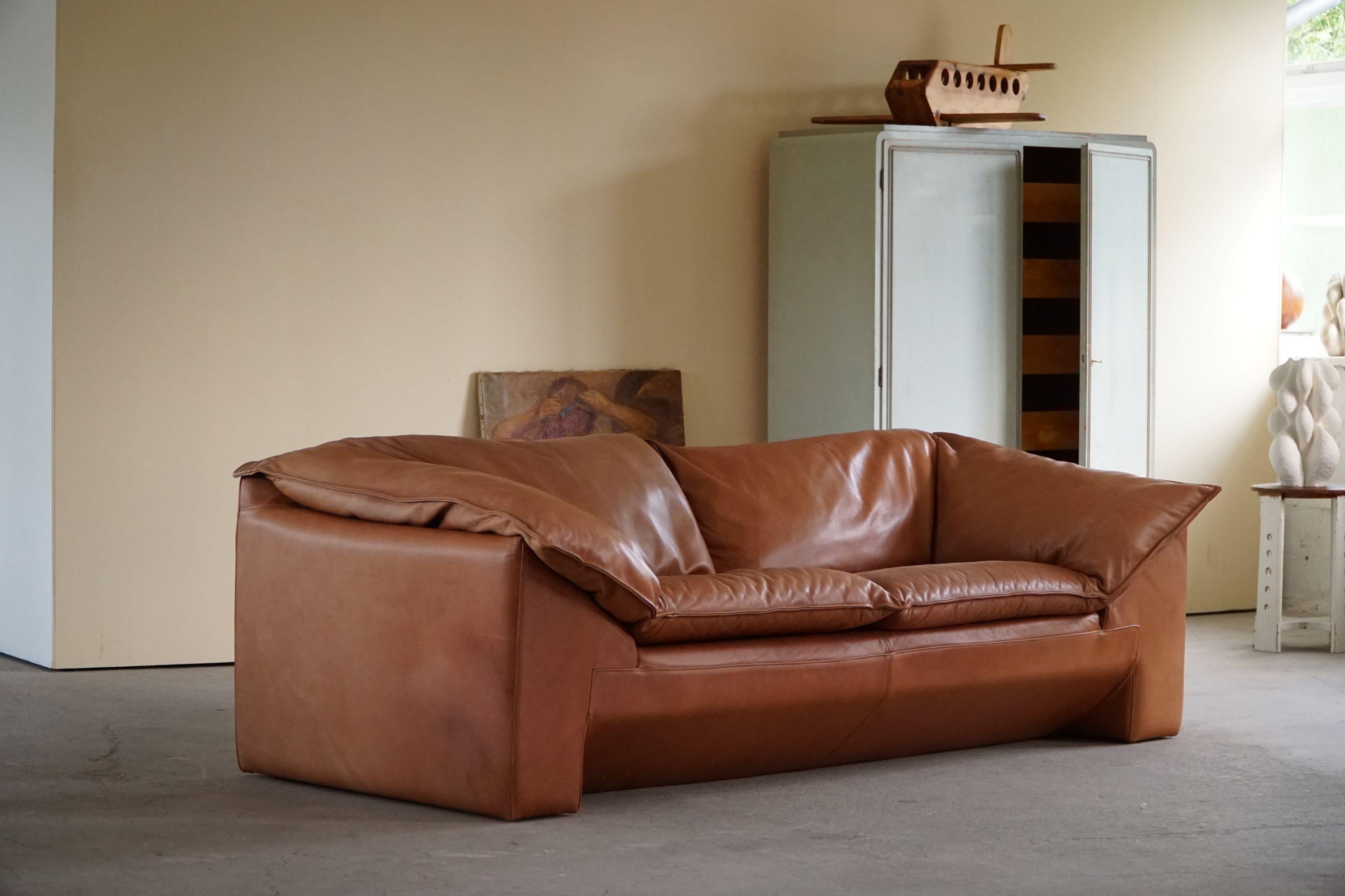 Stunning classic Danish 2.5 seater sofa in cognac brown leather. Designed by Jens Juul Eilersen for Niels Eilersen, Denmark, 1970s. The design reminds us of some of the best Italian classics. The overall impression in this vintage piece is really