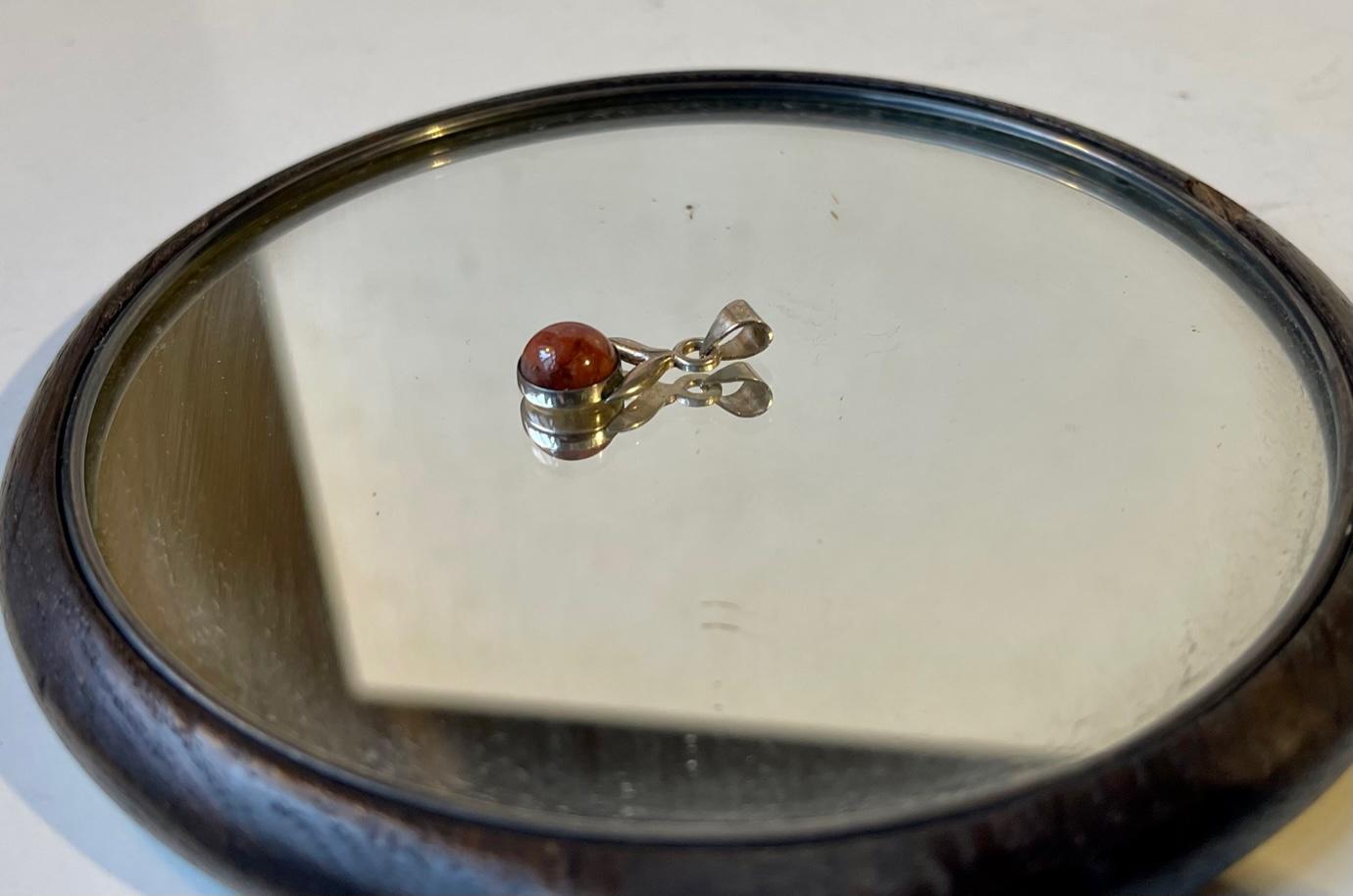Small rare and early 1970s pendant by the Danish silversmith N. E. From. This florally inspired pendant has a polished insert of Danish 'red' amber. Hallmark: From, 925s. Measurements: H: 22 mm, Diameter: 0.6 mm.


