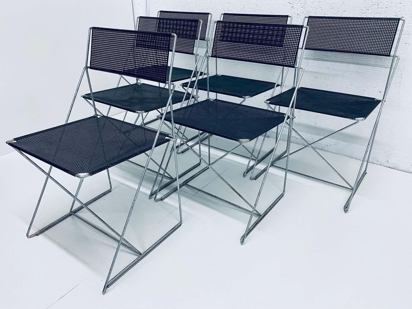 Three pairs of dining chairs in X-line, made of steel rods and black enameled perforated steel backs and seats. Designed by Niels Jorgen Haugesen for Magis. These chairs are in original condition with wear and are stackable. Made in Denmark.