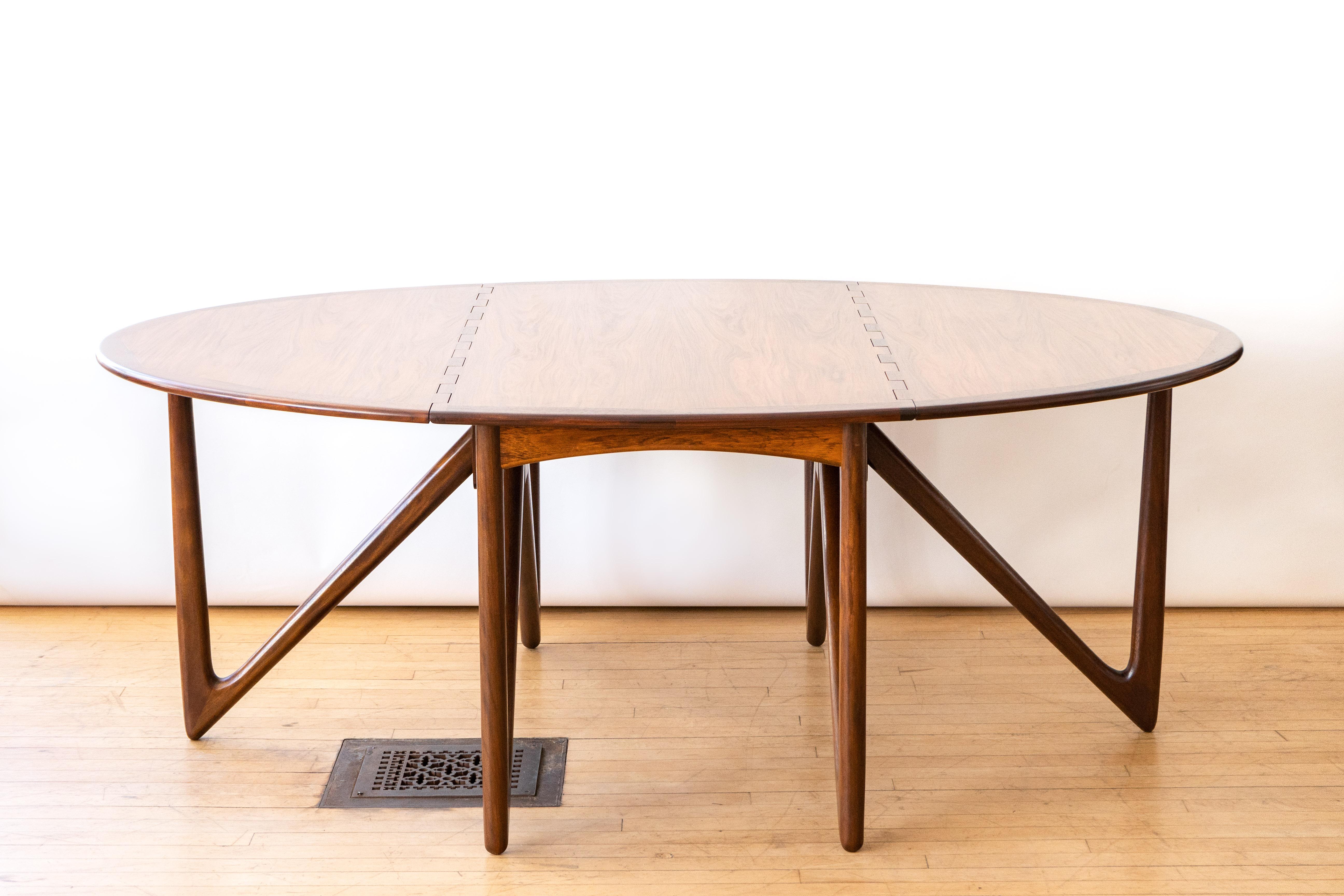 Denmark, ca. 1960s. A stunning drop-leaf dining table by Niels Koefoed for Koefoeds Hornslet. Features rosewood construction with generous oval top supported by sculptural angled legs. Thoughtful hinged detail and inlaid border enhances overall