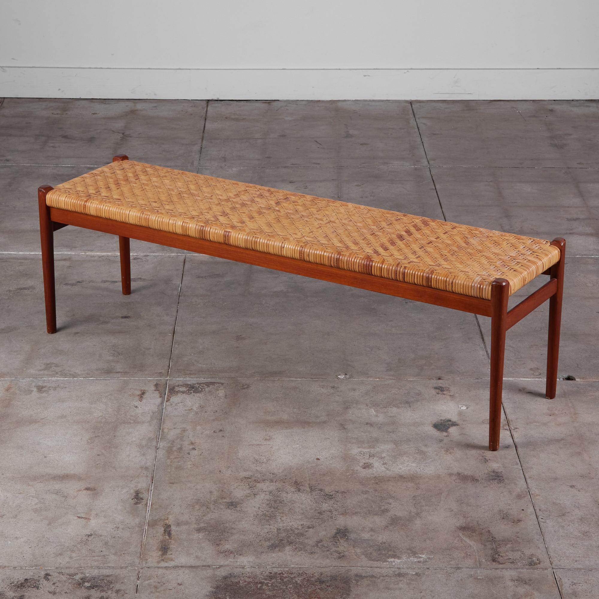 Niels Møller's teak and cane bench for his family’s company, JL Møllers Møbelfabrik, Denmark, c.1960s. The bench features an oiled teak frame and legs with with woven cane.

Retains J.L. Møllers - Made in Denmark stamp on the underside of the