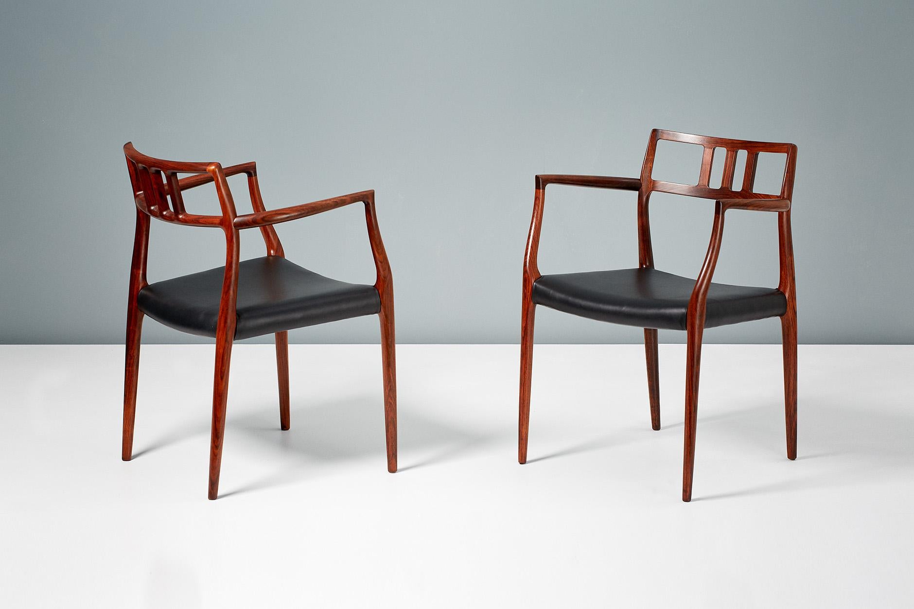A pair of Model 64 rosewood armchairs produced by J.L. Moller Mobelfabrik in Denmark, circa 1966. The stunning rosewood frames have been refinished and the seats newly covered in premium aniline black leather.