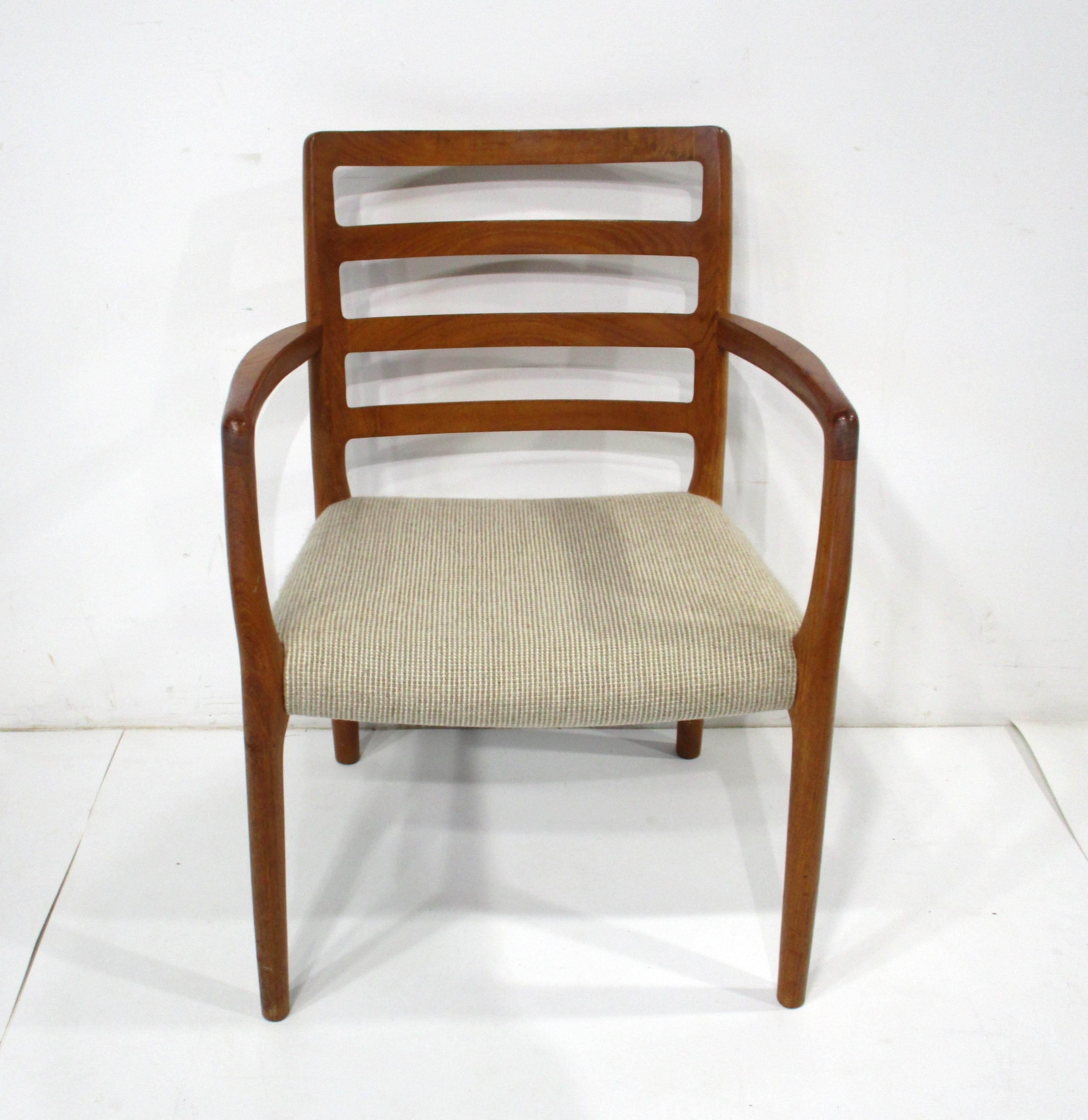 A set of six sculptural teak wood framed dining chairs consisting of four side chairs and two arm chairs . The seat backs have a slight curve and the woven oatmeal toned upholstered fabric to the seat bottoms offer great comfort . Retains the makers