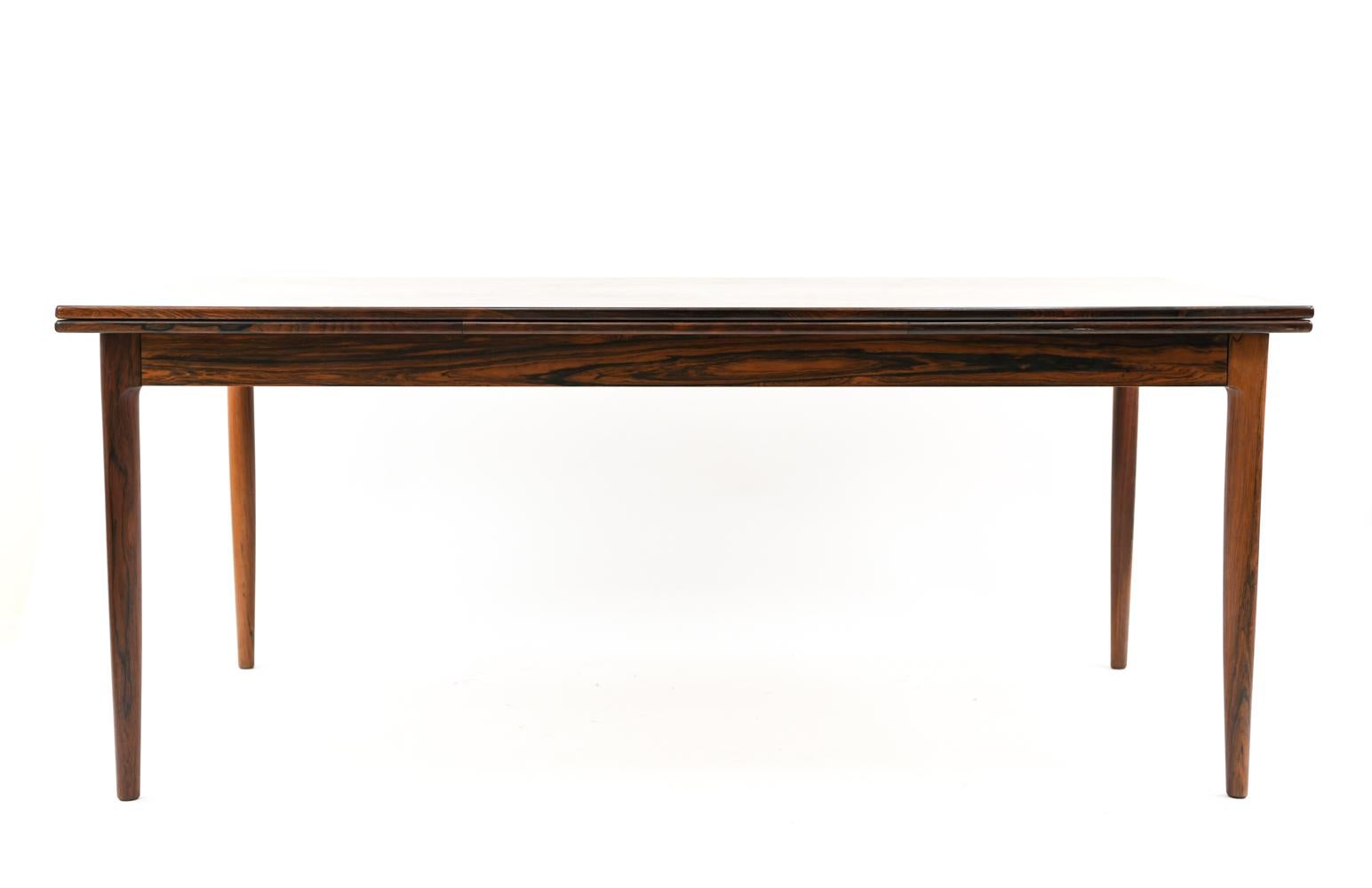 A rare, large Danish midcentury dining table designed by Niels O. Møller for J.L Møllers Møbelfabrik, circa 1960s, in rosewood with a bookmatched veneered rosewood top. A clean, refined rectangular form with rounded, tapered legs give this piece a