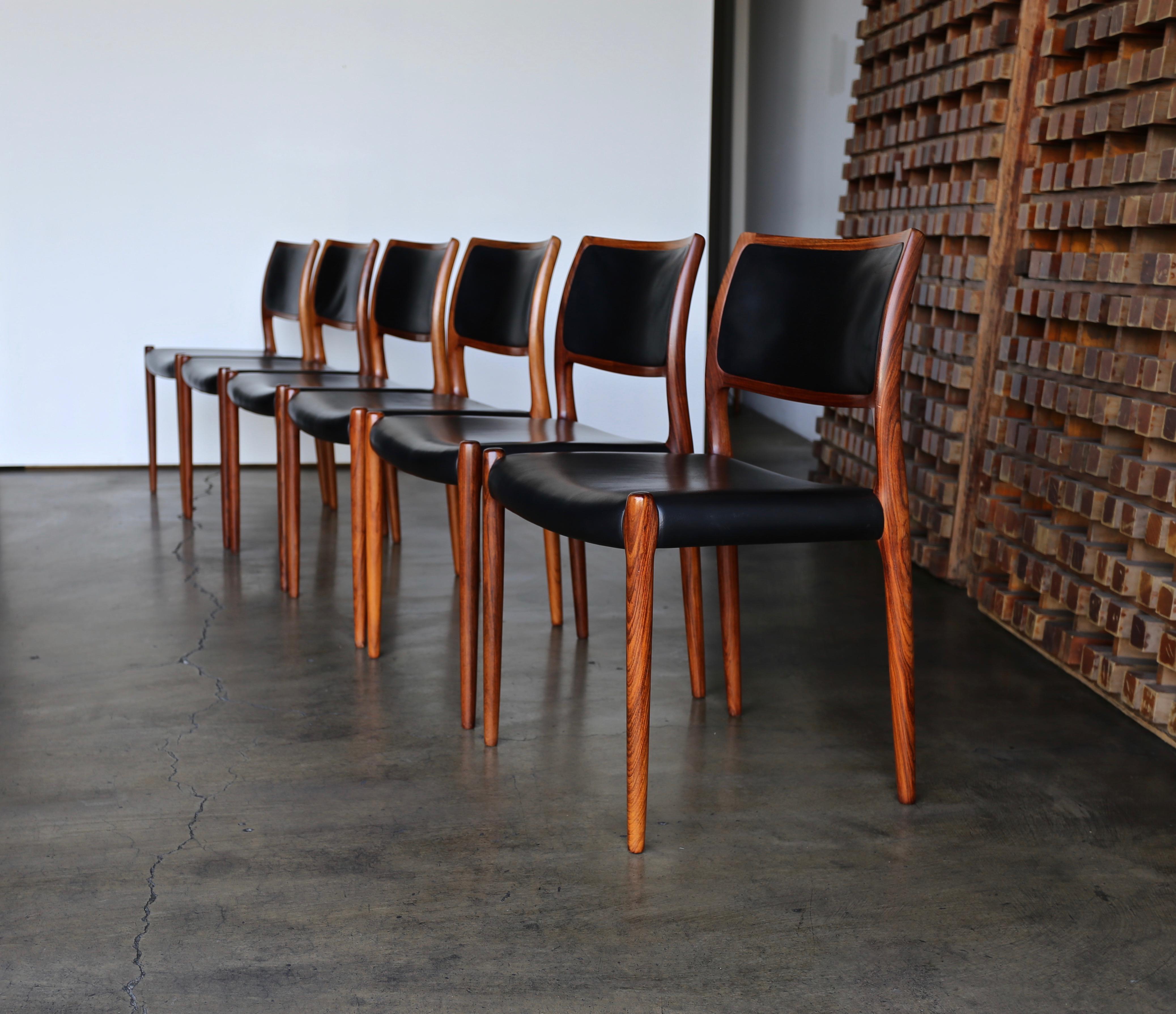 Niels O. Møller rosewood and leather dining chairs for J.L. Møllers Møbelfabrik, Denmark, circa 1976. A set of six. This set retains its original black leather. Each chair is stamped with the makers mark to the bottom.