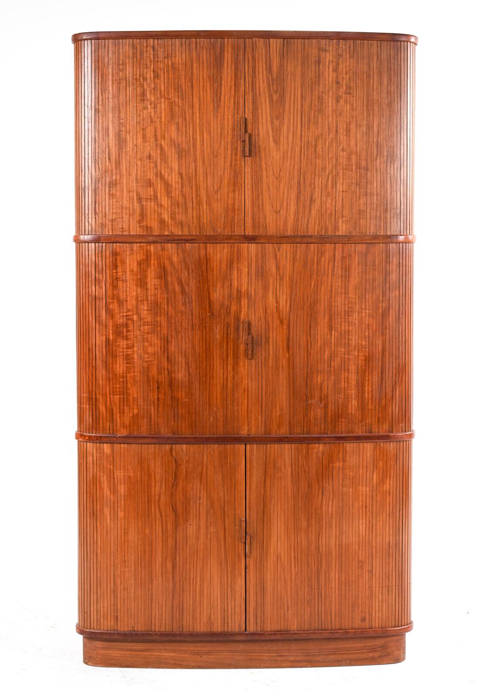 An unusual and functional corner cabinet in teak wood with fun rounded form, designed by Niels O. Møller for J.L. Møller and produced in the 1960's. Three sets of tambour doors slide apart to reveal two drawers and a plethora of adjustable shelves