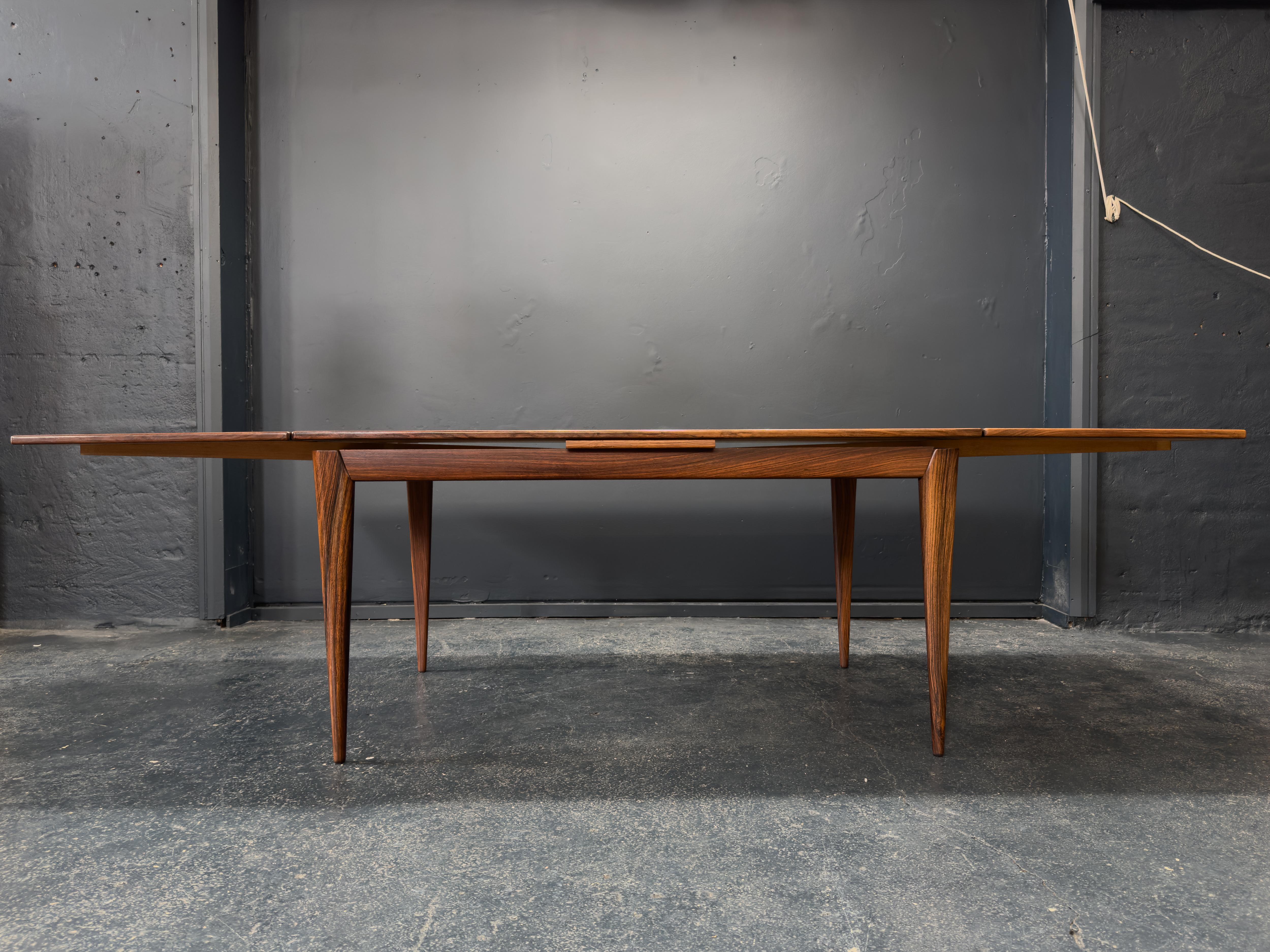 Les lignes épurées de la table sont complétées par des pieds joliment fuselés et des bords subtilement arrondis, créant un profil léger et sculptural. Il comprend deux rallonges qui s'intègrent parfaitement au design, ce qui en fait un choix
